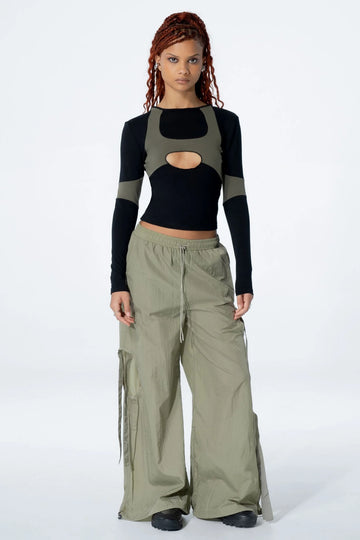Woman wearing a black long-sleeve top with a cut-out design and pants on a white background