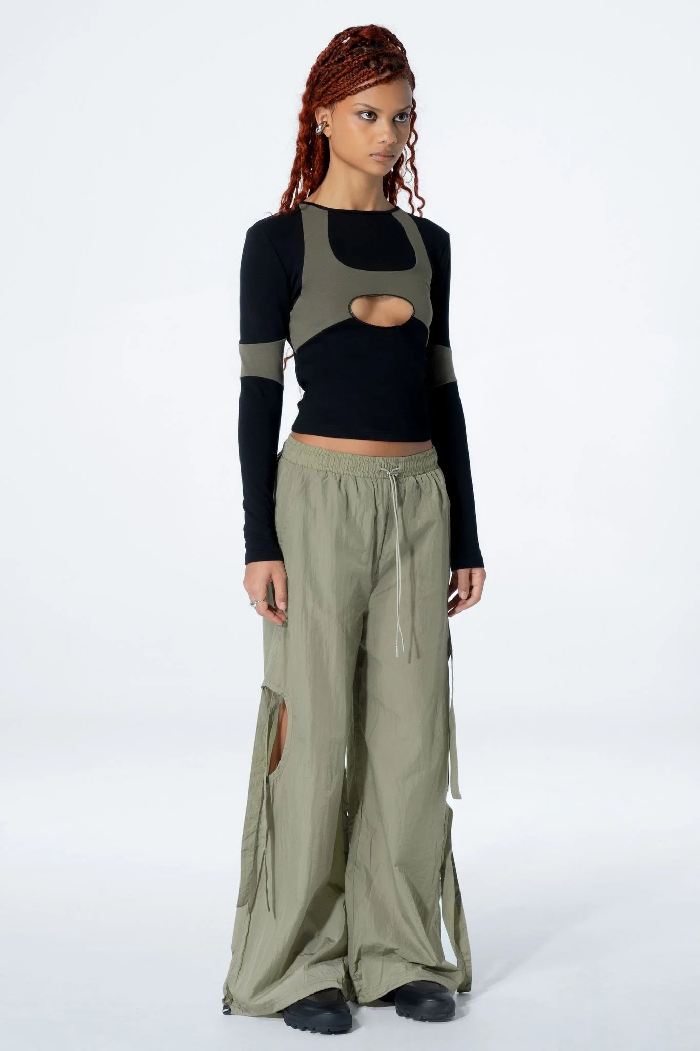 Woman wearing a black long-sleeve top with a cut-out design and pants on a white background