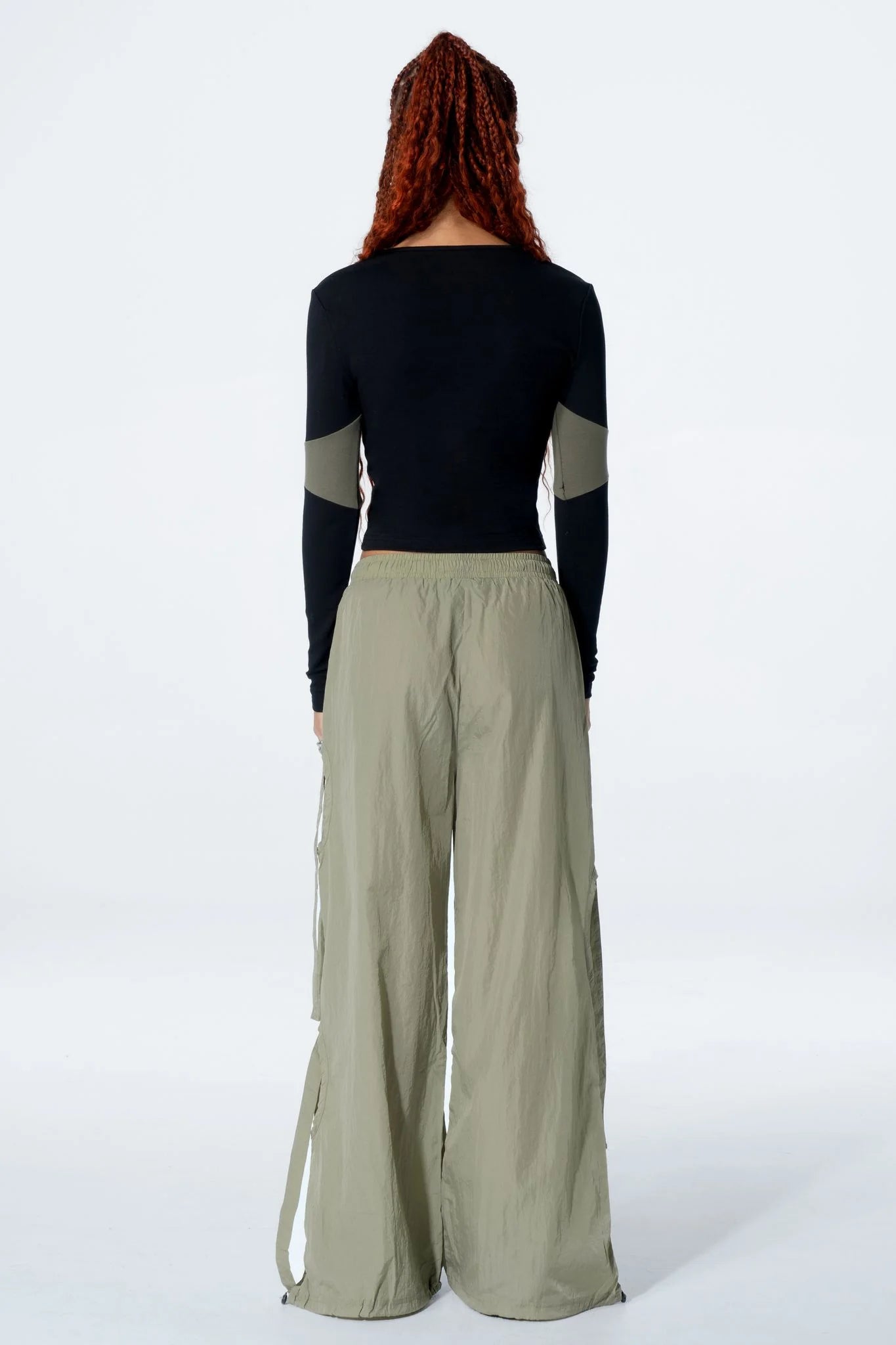 Woman wearing a black long-sleeve top with a cut-out design and pants on a white background