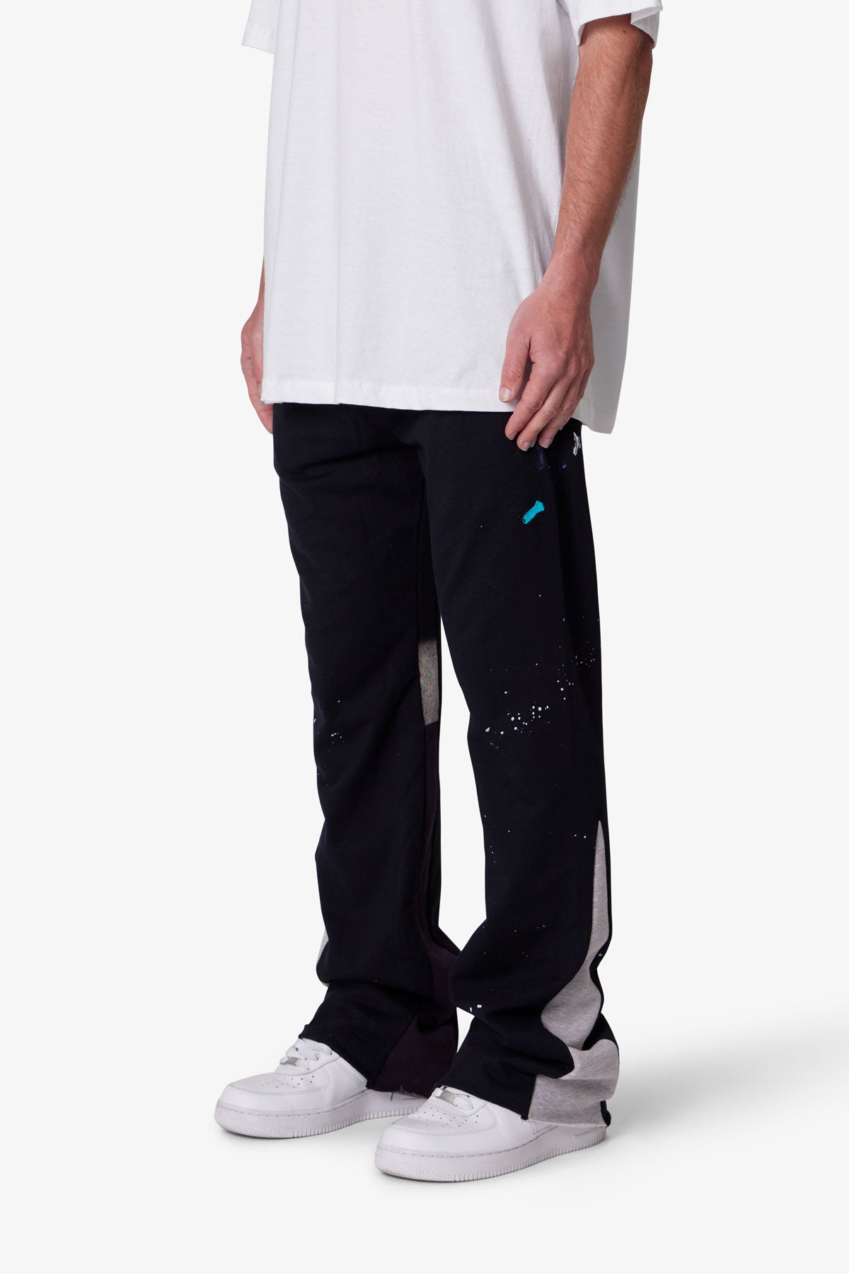Person wearing black pants with white accents on a white background