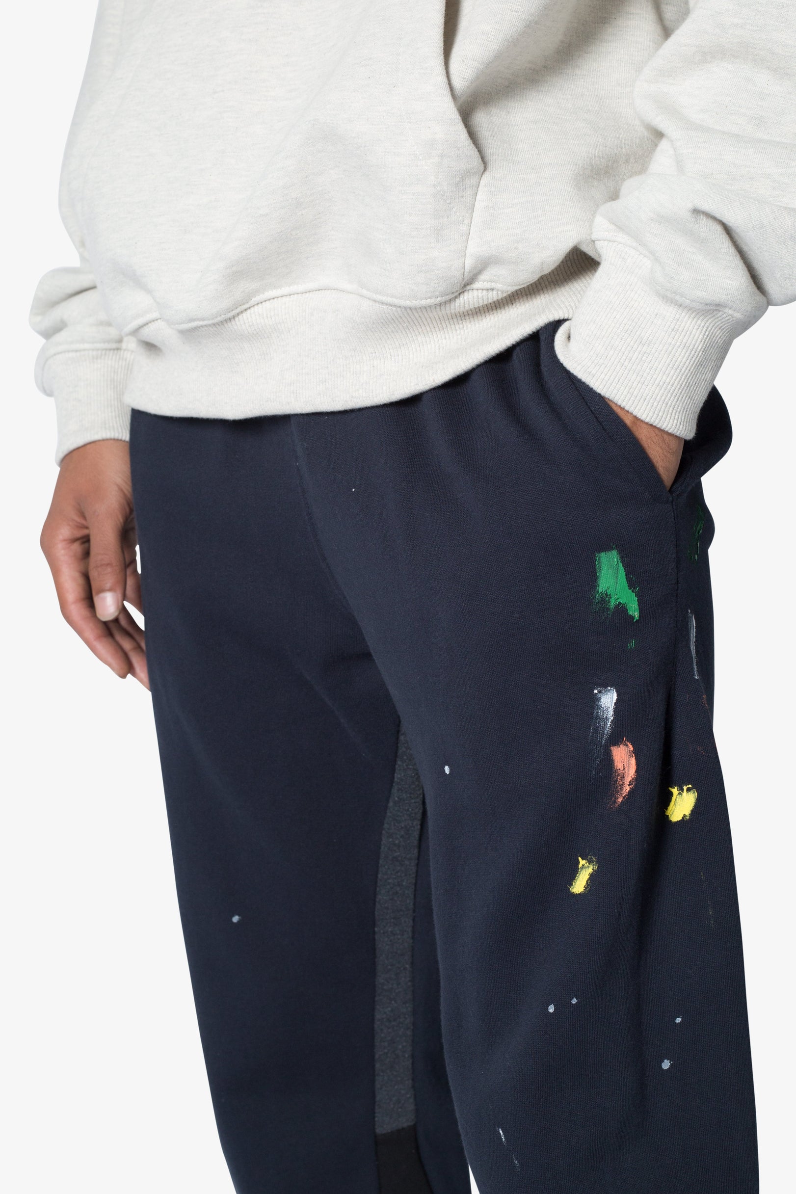 Navy sweatpants with colorful graphic designs worn by a person against a white background