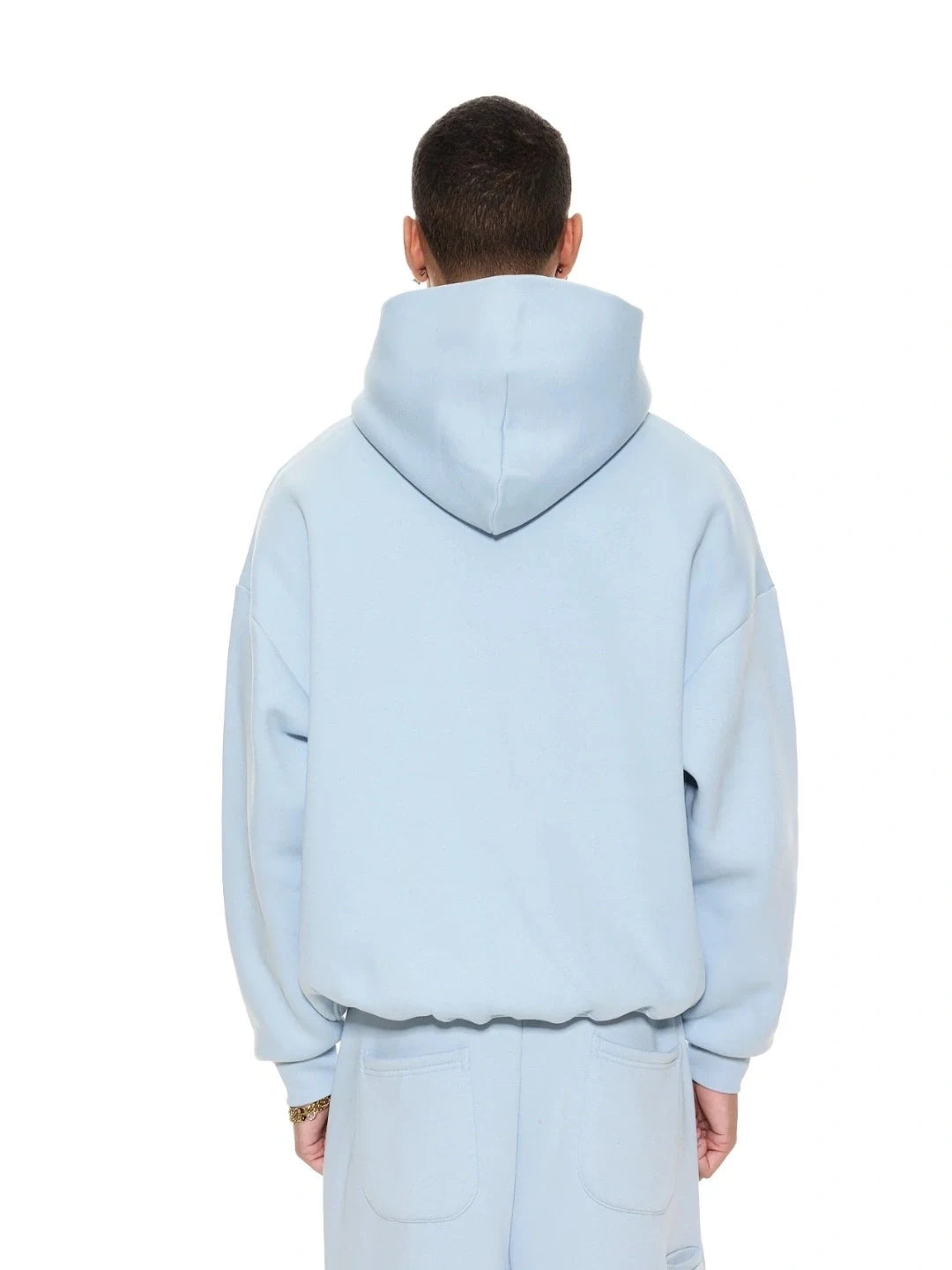 Person wearing a light blue hoodie and pants on a white background