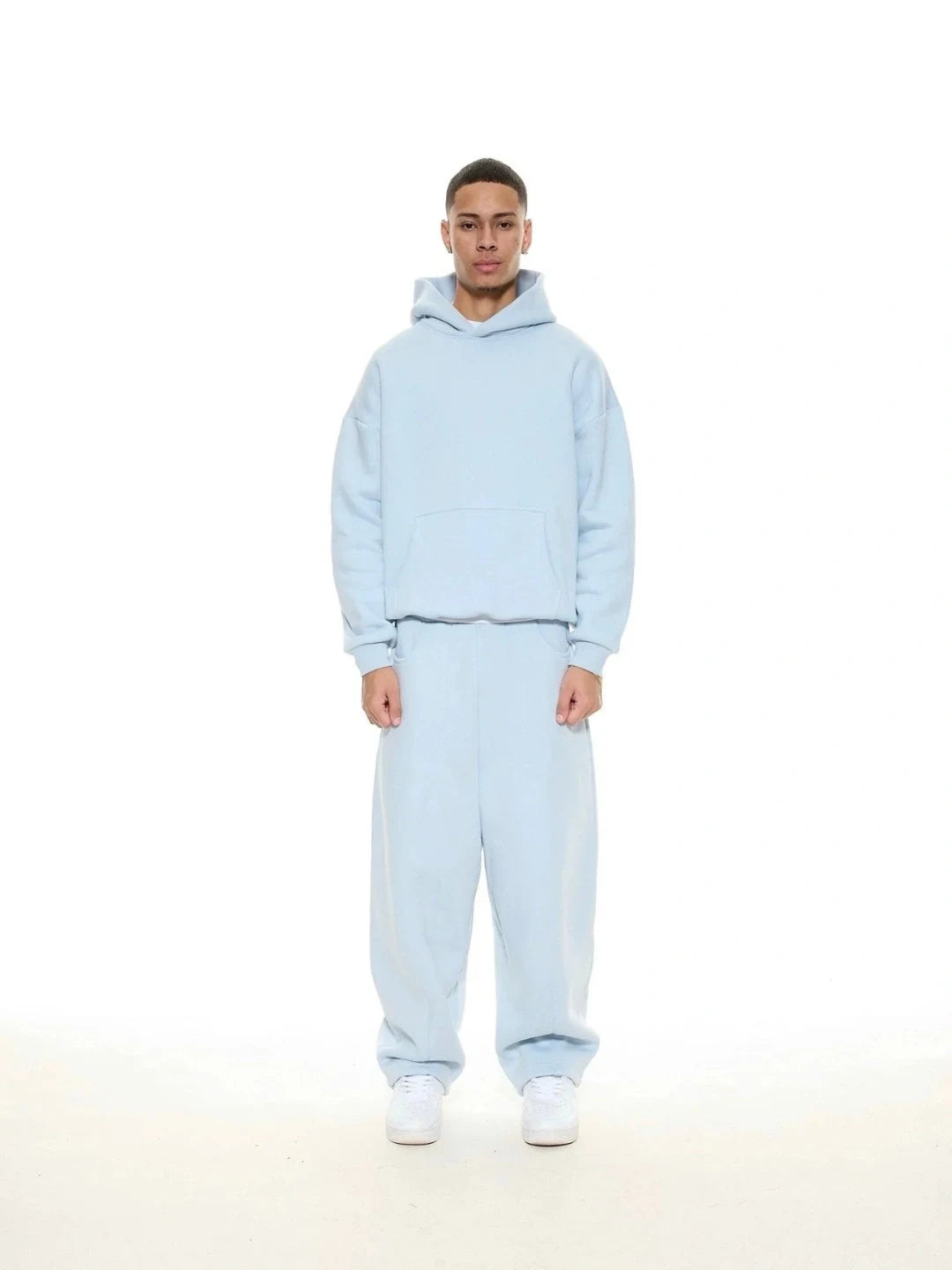 Person wearing a light blue hoodie and pants set on a white background