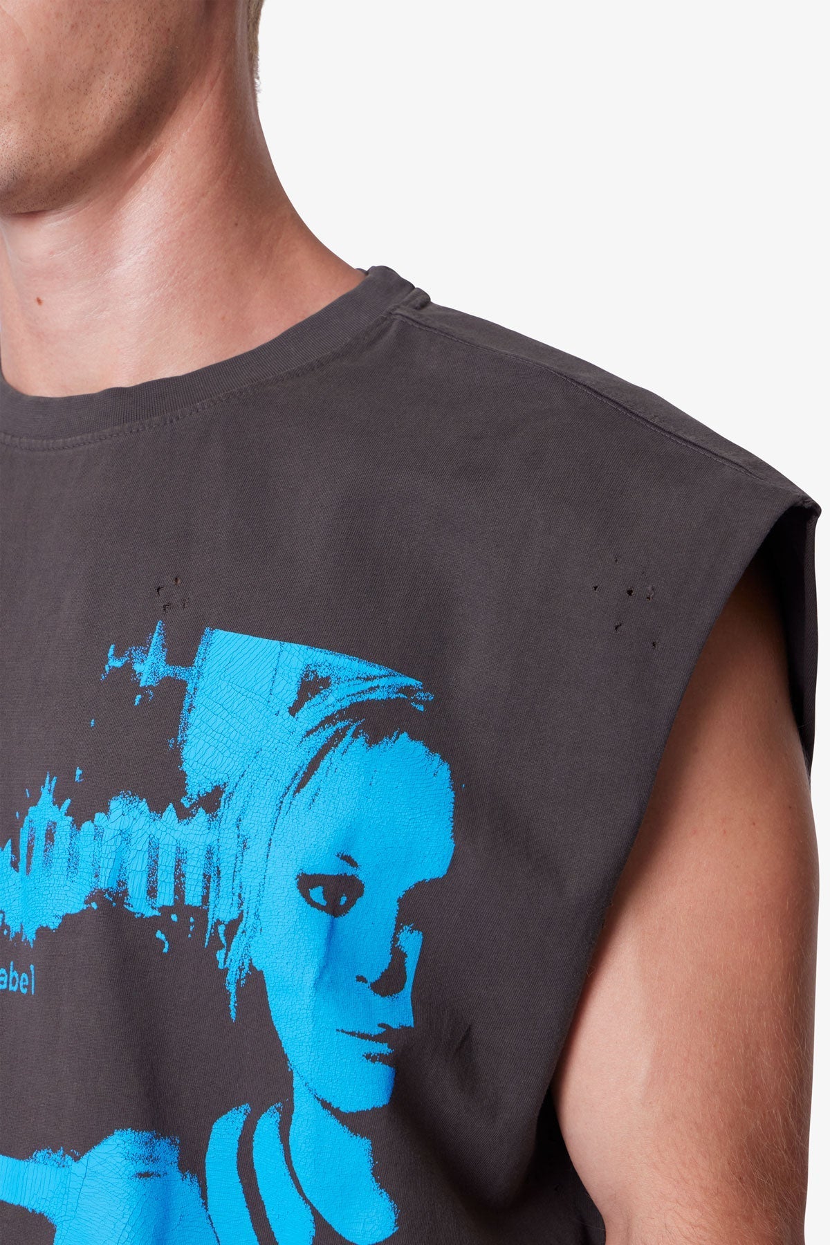 Person wearing a sleeveless shirt with a blue graphic design on a plain background
