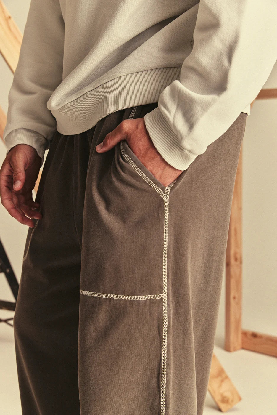 Person wearing a light grey sweatshirt and brown sweatpants with a blurred background