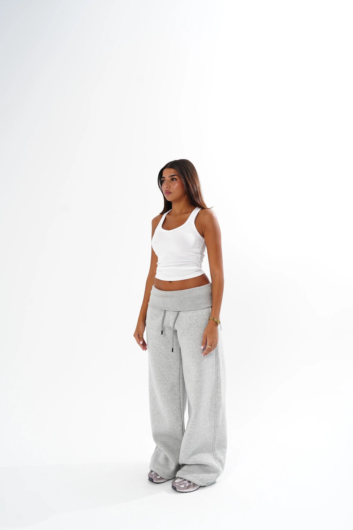A woman modeling a white ribbed tank top and light grey wide-leg sweatpants against a clean white studio background.