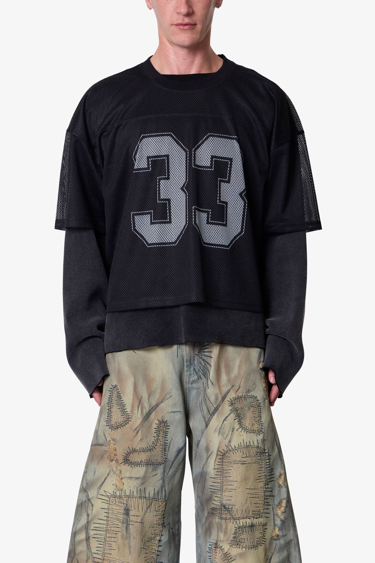 Person wearing a black oversized sweatshirt with the number 33 on a plain background