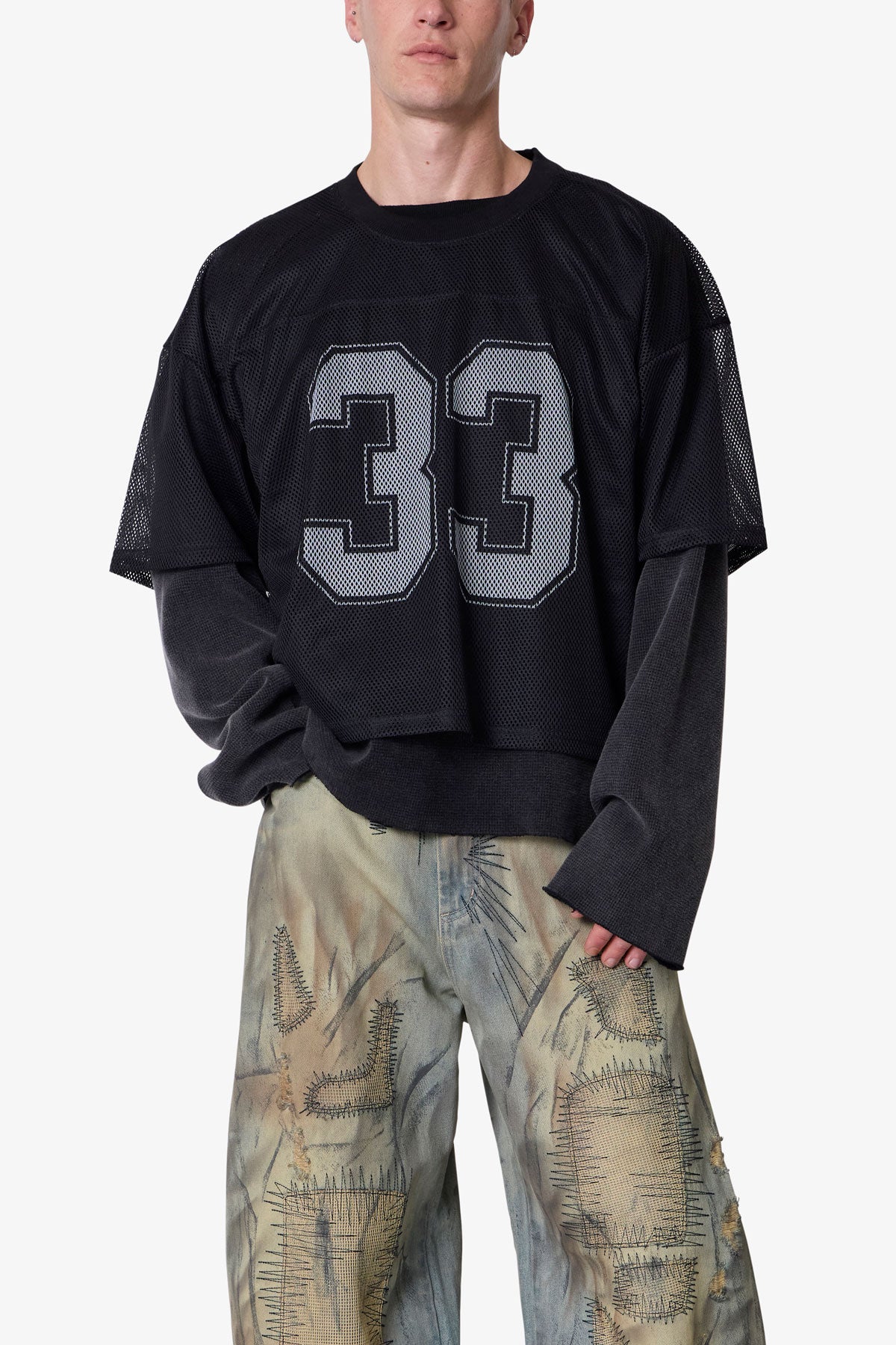 Person wearing a black oversized jersey with the number 33 on a white background