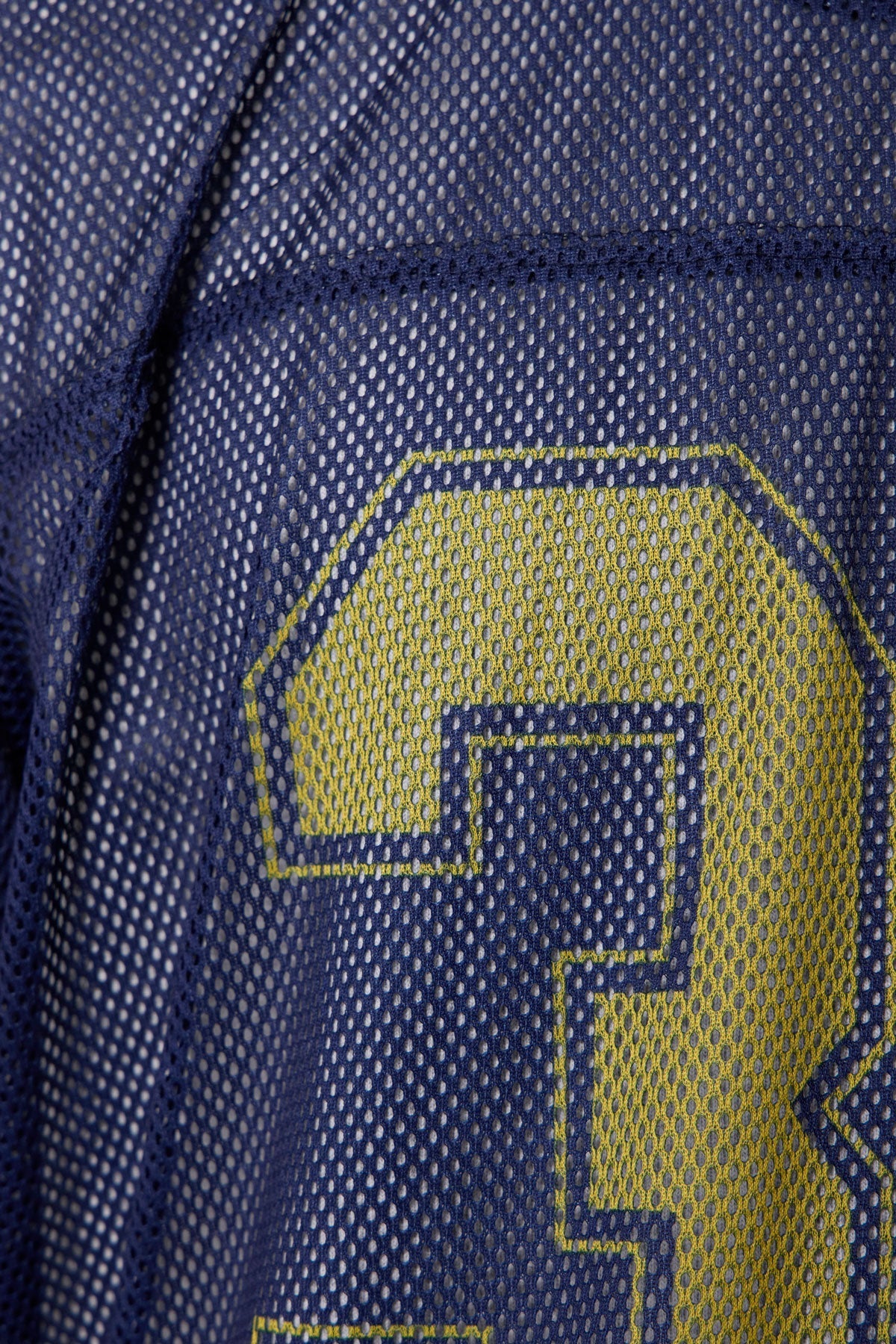 Close-up of a blue jersey with a yellow logo on a textured fabric background