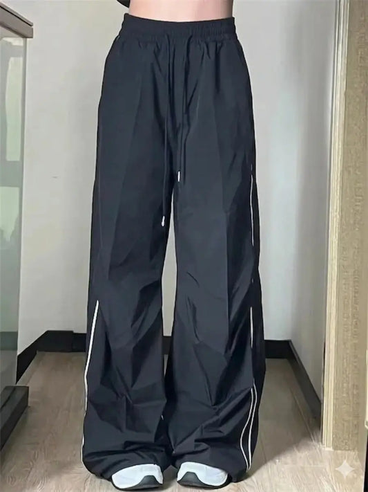 Black wide-leg pants with white stripes worn by a person indoors.