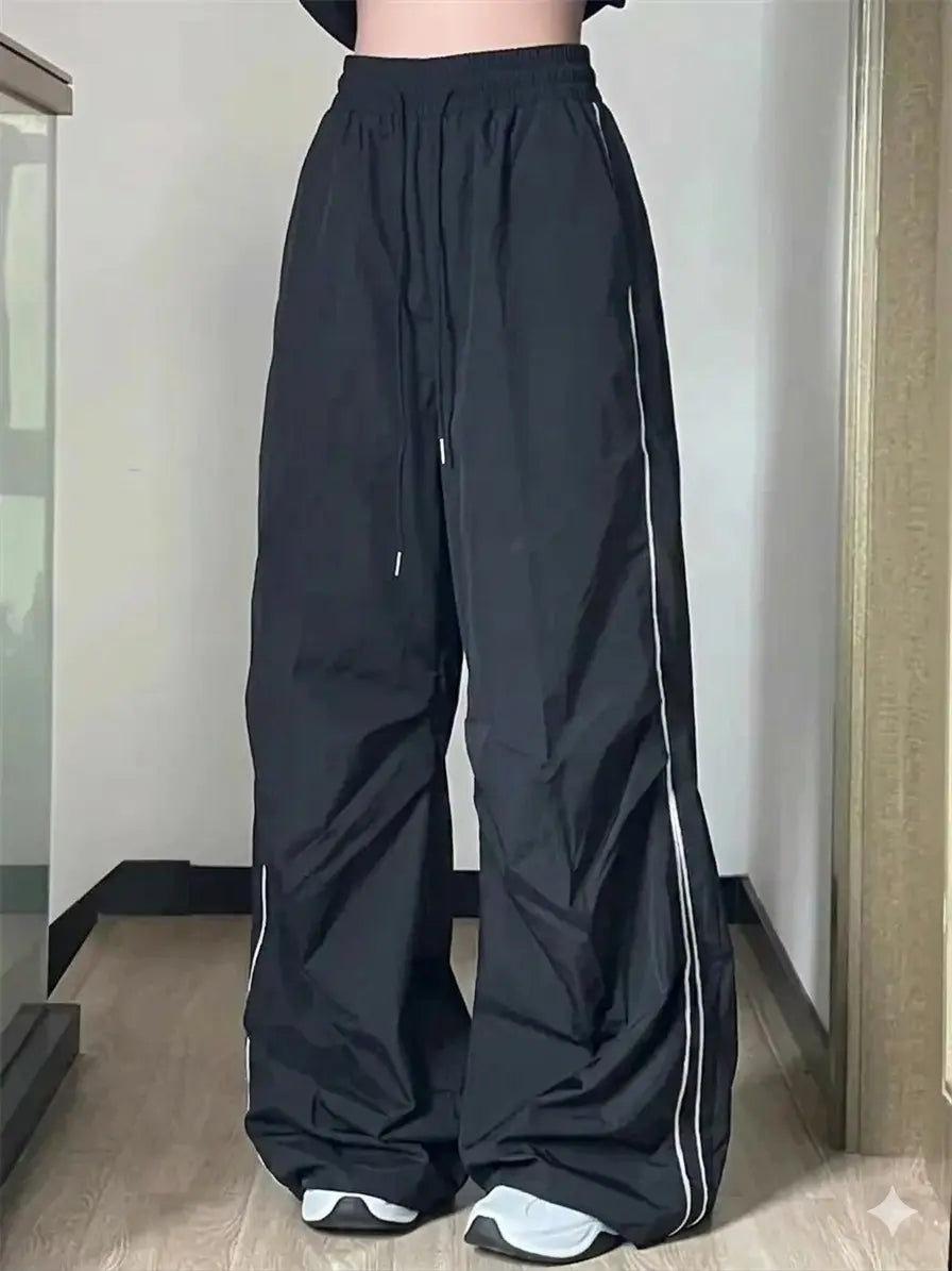 Black wide-leg pants with a white stripe on a neutral background