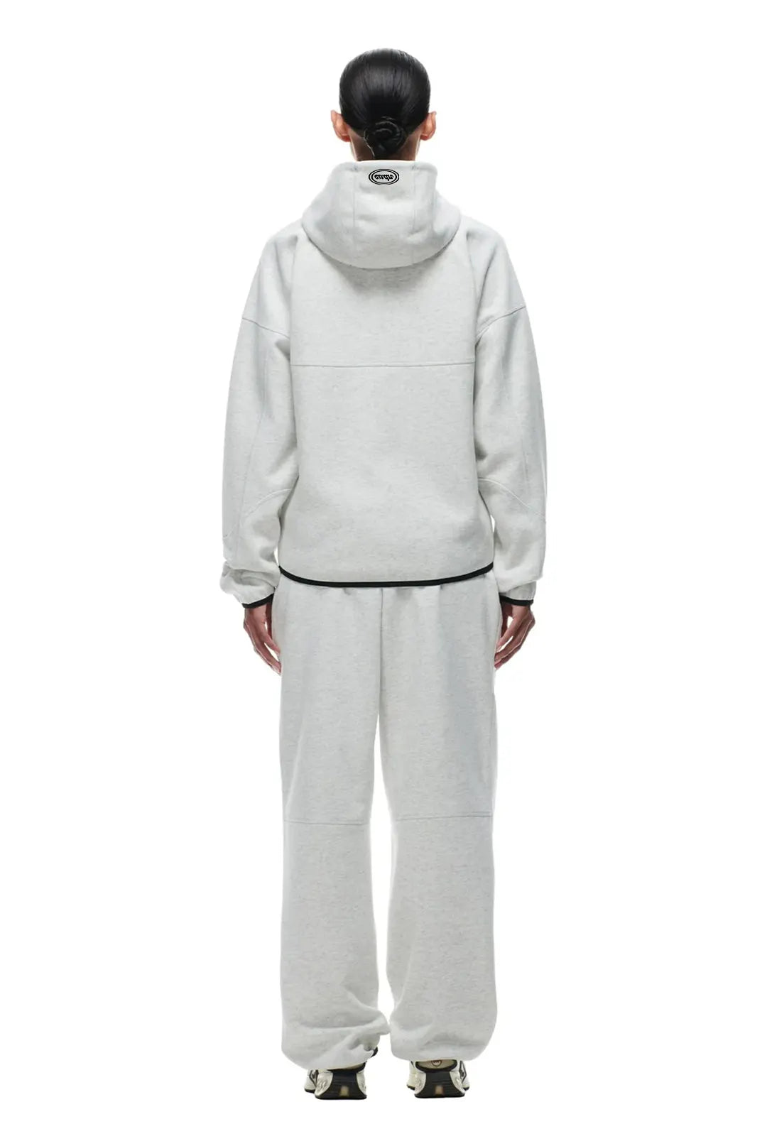 Person wearing a light gray tracksuit on a white background