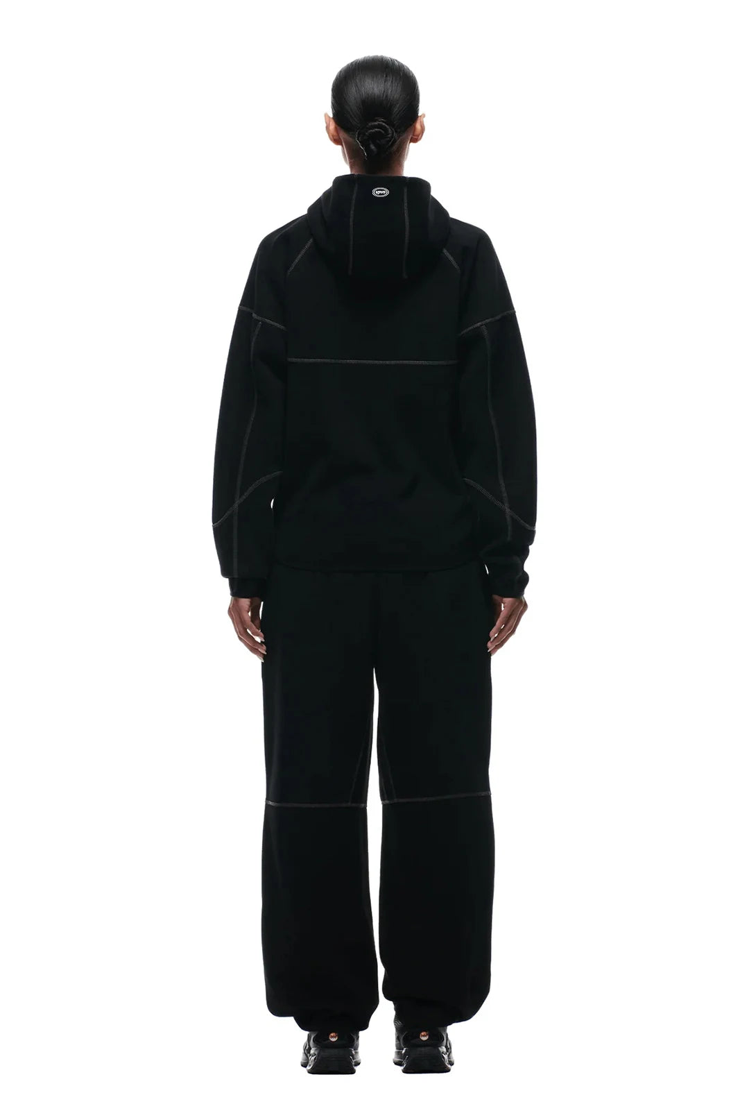Person wearing a black outfit with a hood on a white background