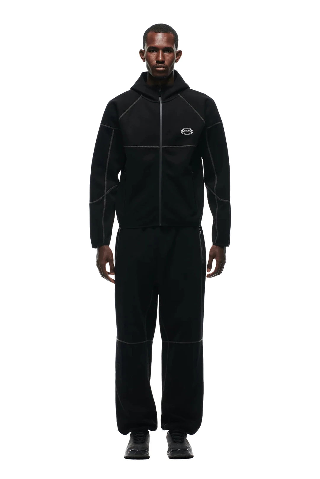 Man wearing a black fleece outfit with a brand logo on a white background