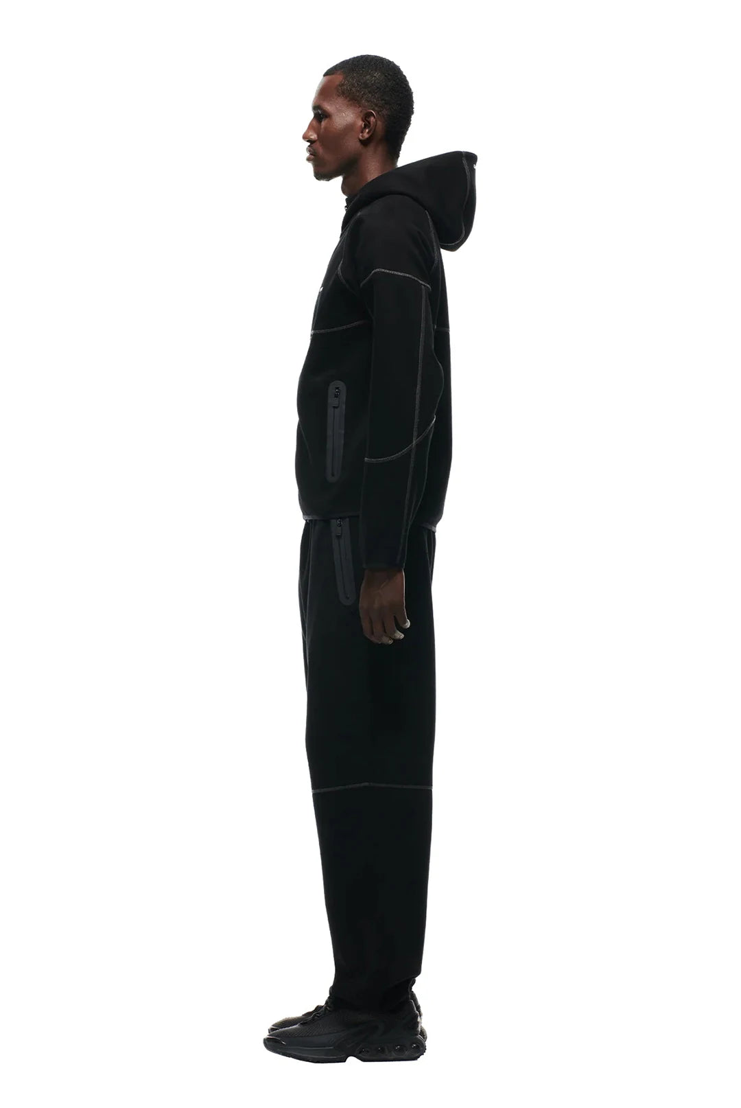 Person wearing a black hooded jumpsuit on a white background