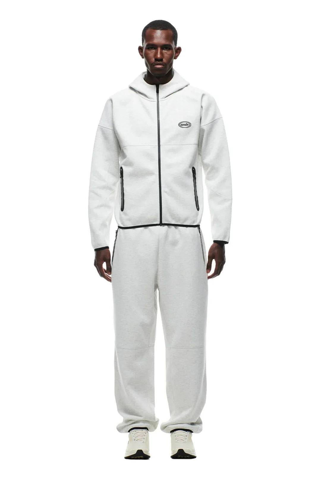 Person wearing a white tracksuit with a brand logo on a white background
