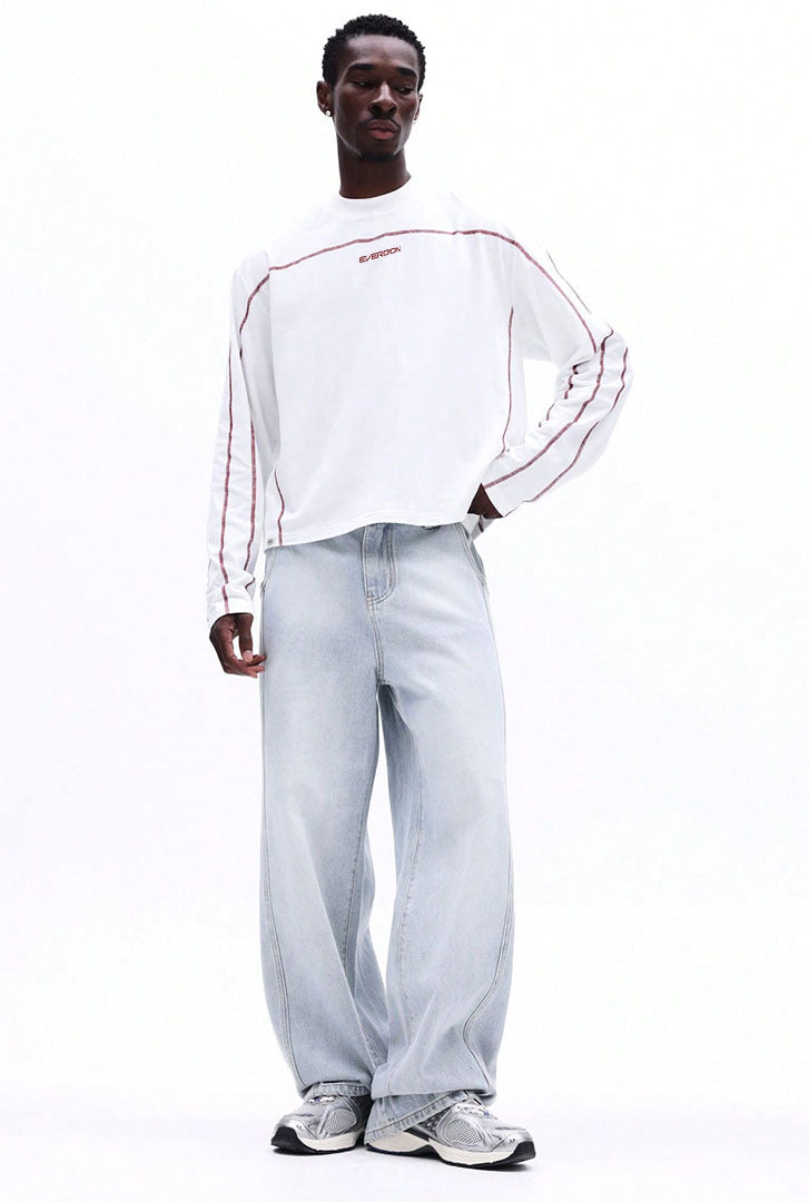 Person wearing a white long-sleeve shirt with red accents and light grey pants on a white background