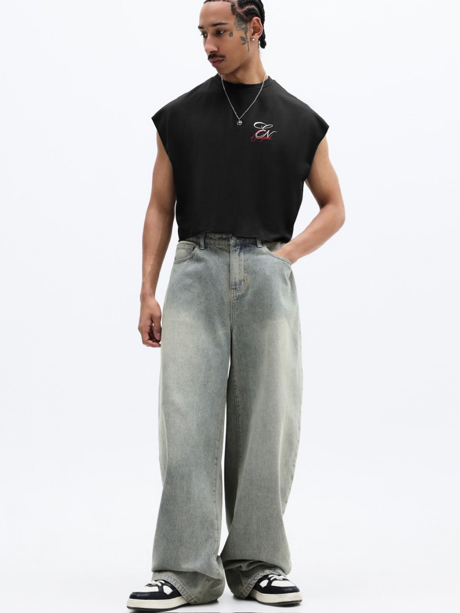 Person wearing a black sleeveless shirt and light blue jeans on a white background