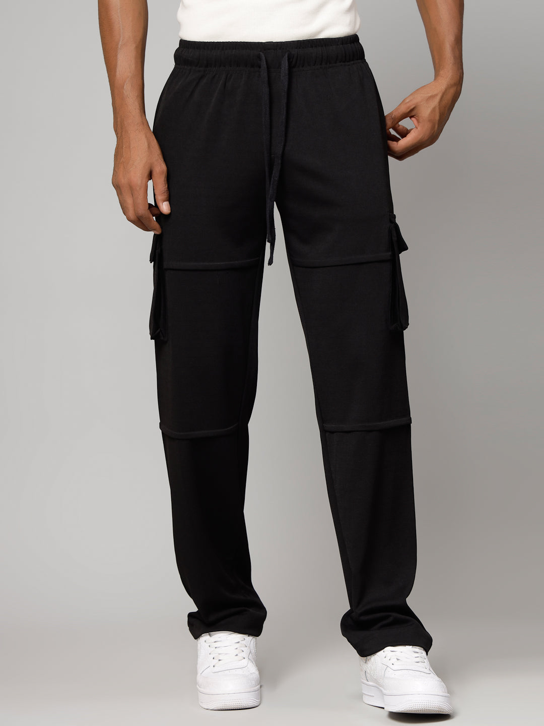 Person wearing black cargo pants on a gray background