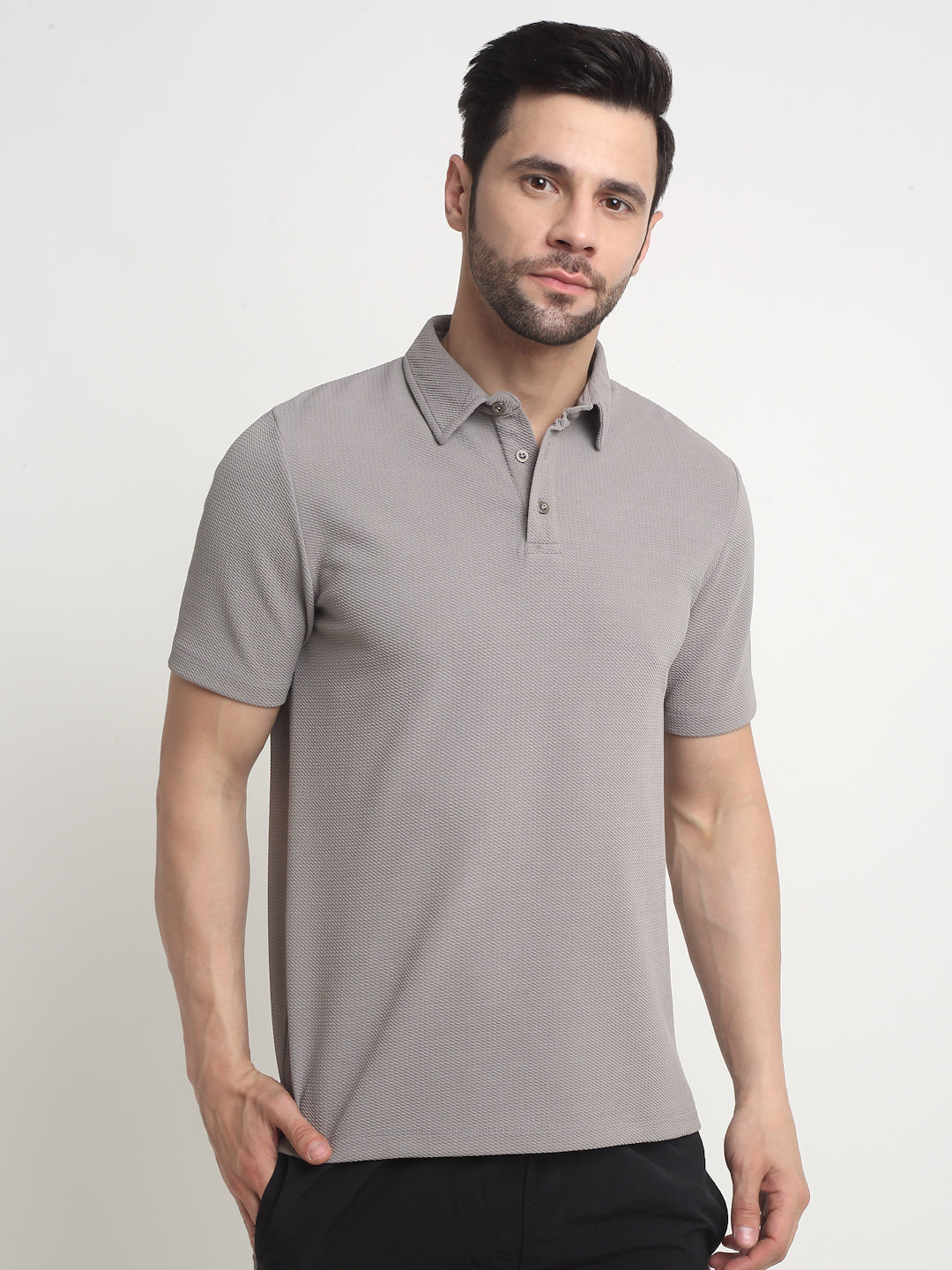 A man wearing a grey waffle knit polo t-shirt with a classic collar, button-up neck, and a polo sleeve design.