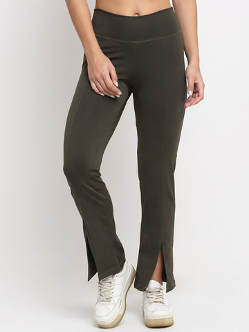 A pair of high waist green yoga pants with front slits and a flared leg design, being modeled by a person wearing white sneakers.