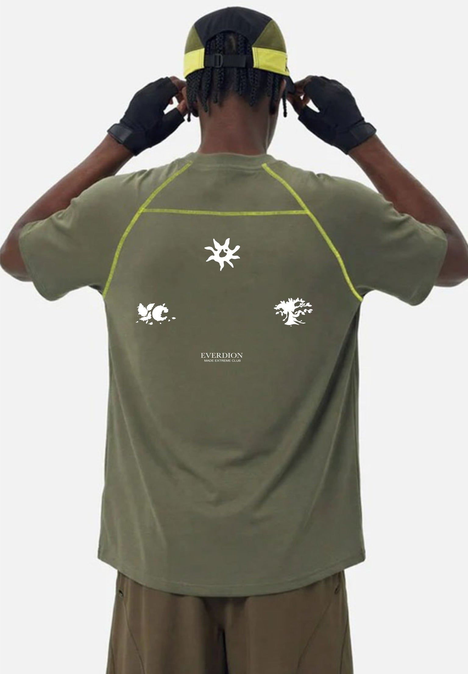 Person wearing a green t-shirt with a logo on the back, standing against a white background