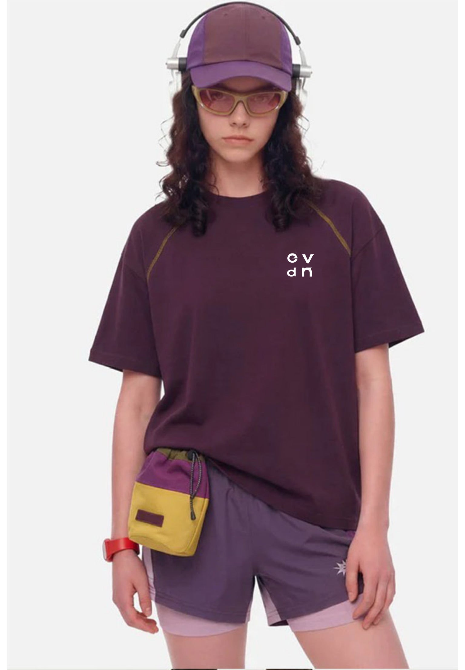 Person wearing a purple t-shirt and shorts with a yellow bag, on a white background