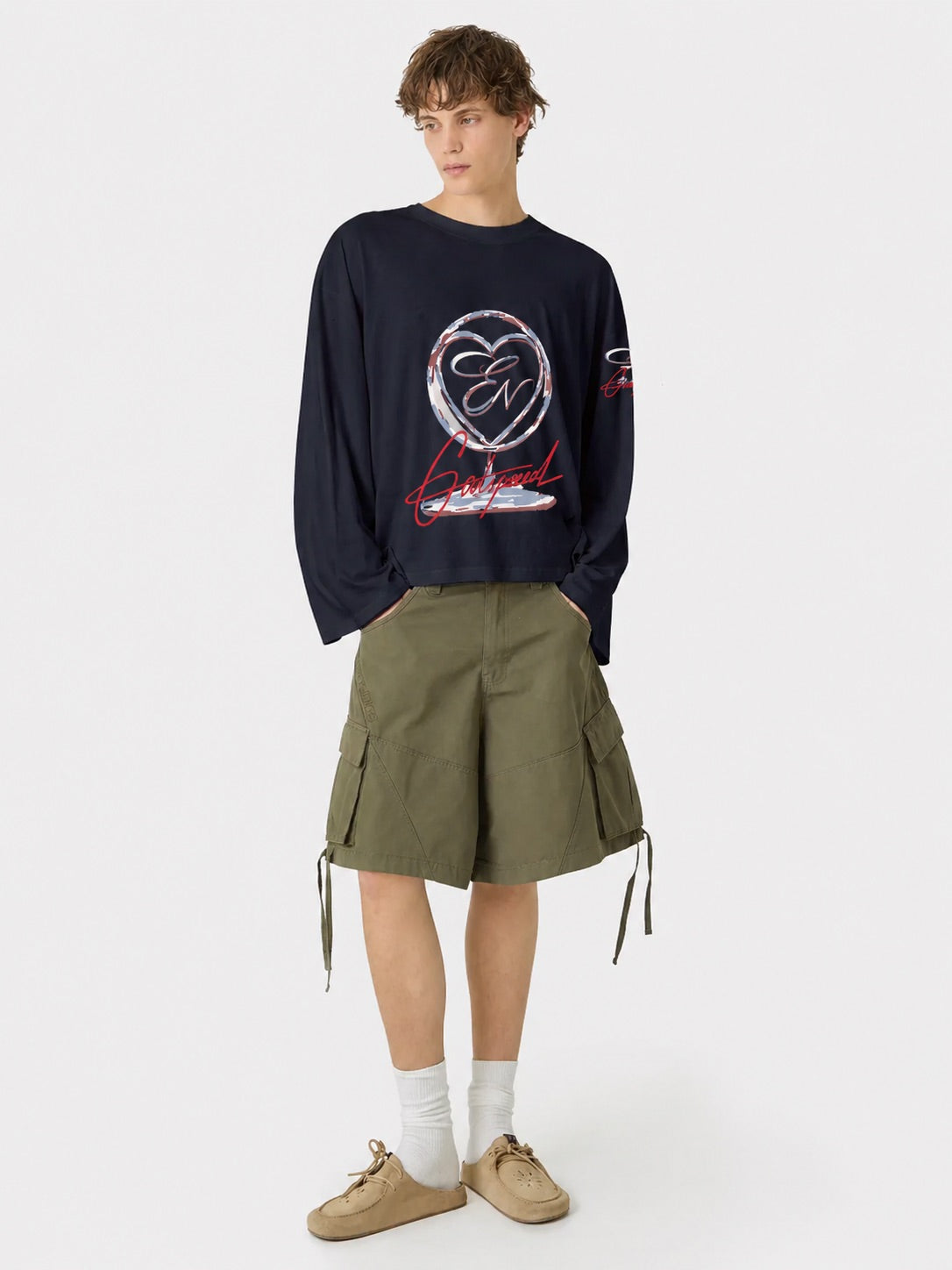 Person wearing a dark blue sweatshirt with a graphic design and green shorts on a white background