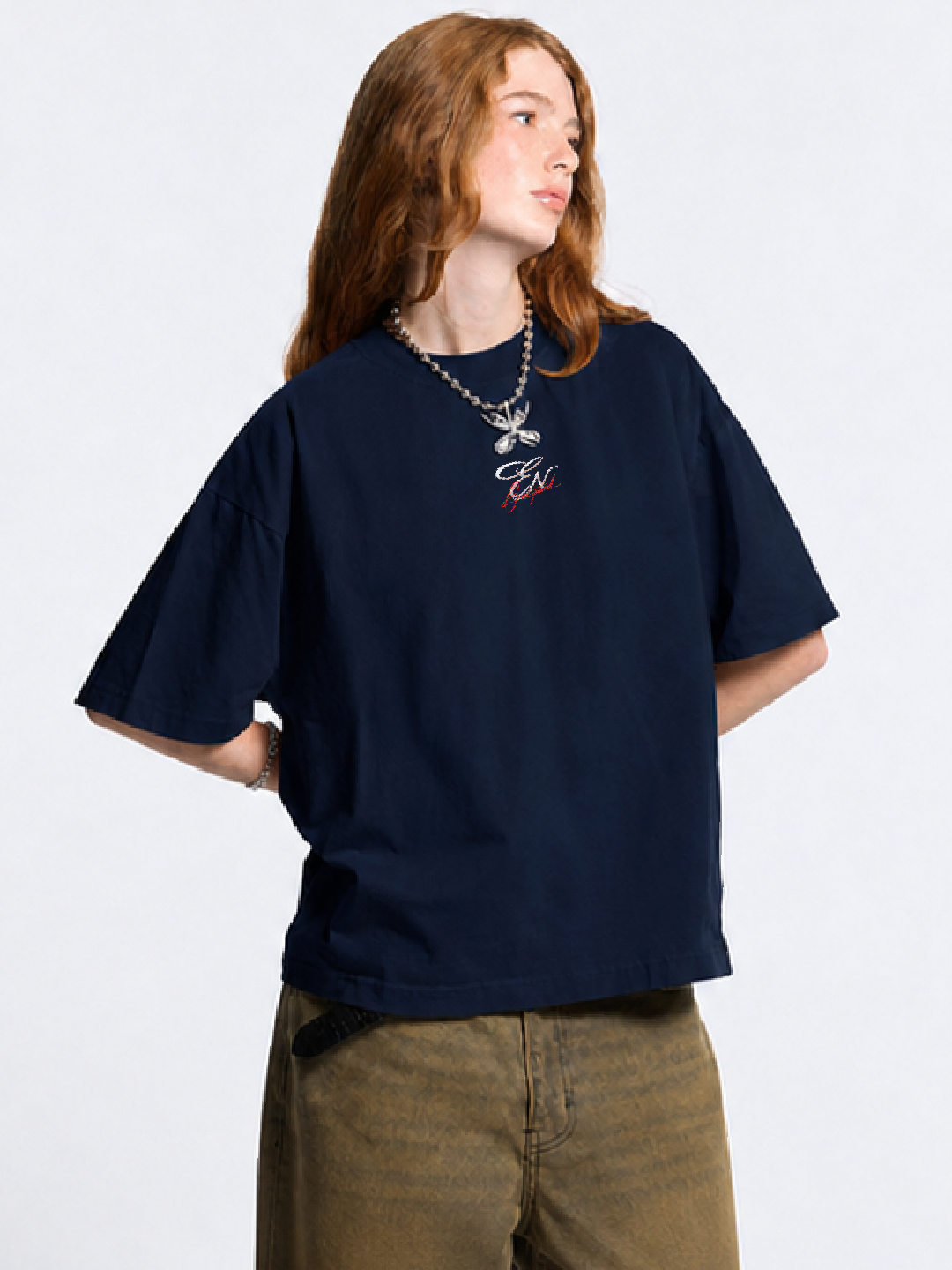Person wearing a navy blue oversized t-shirt with a logo on a white background