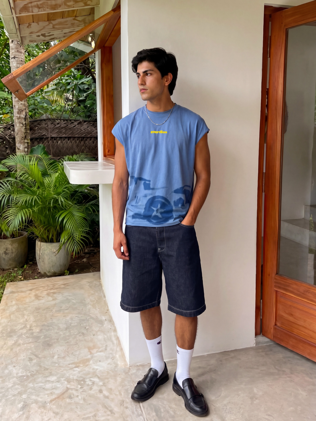 Person wearing a blue t-shirt and dark shorts standing outdoors.