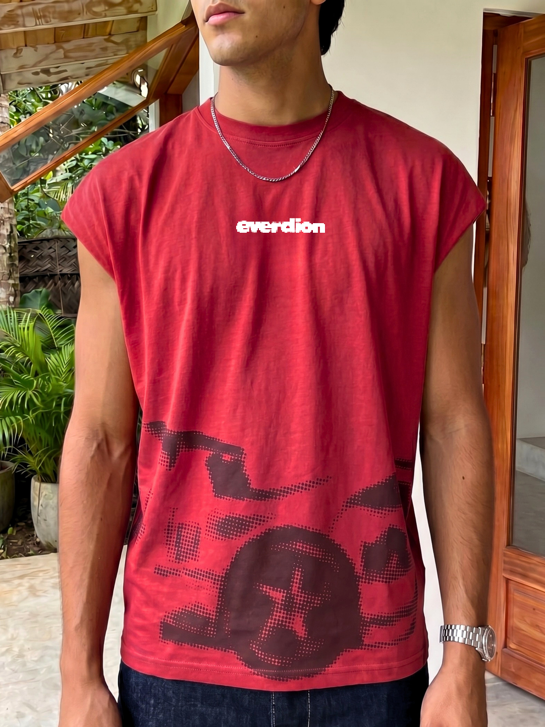 Person wearing a red sleeveless shirt with 'everdion' branding outdoors.