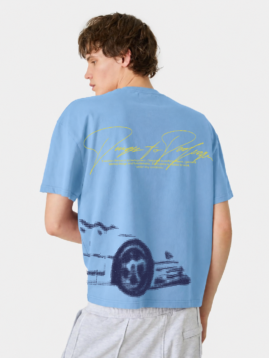 Person wearing a light blue t-shirt with a graphic design and text on the back.