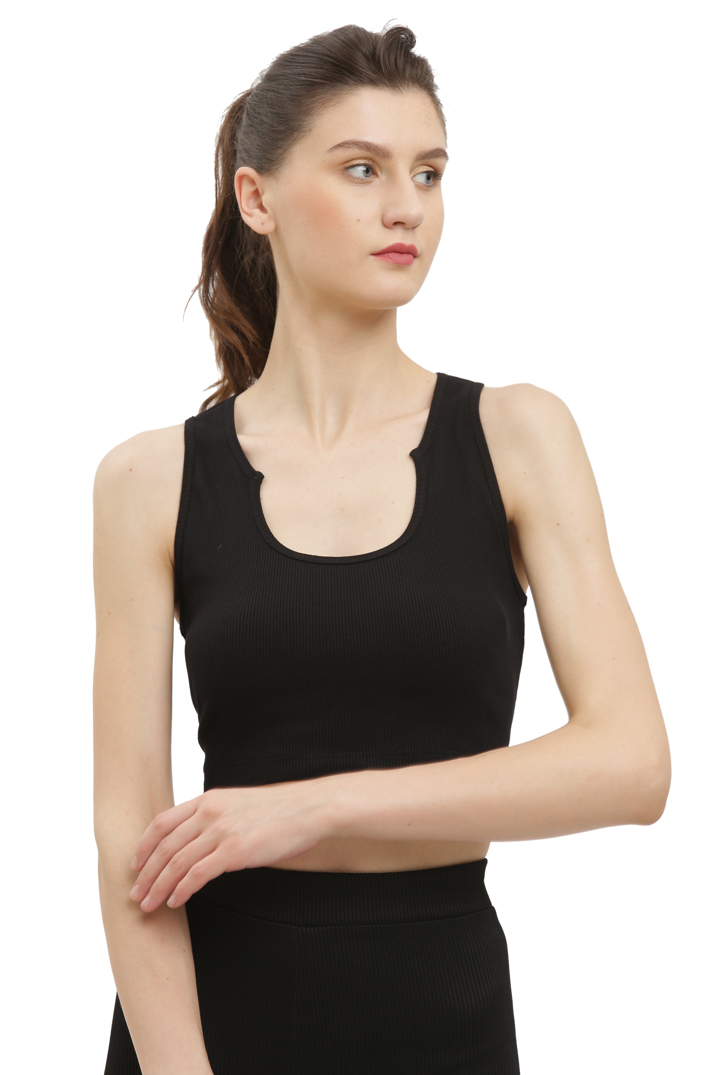 A woman wearing a black rib sleeveless crop top and black pants.