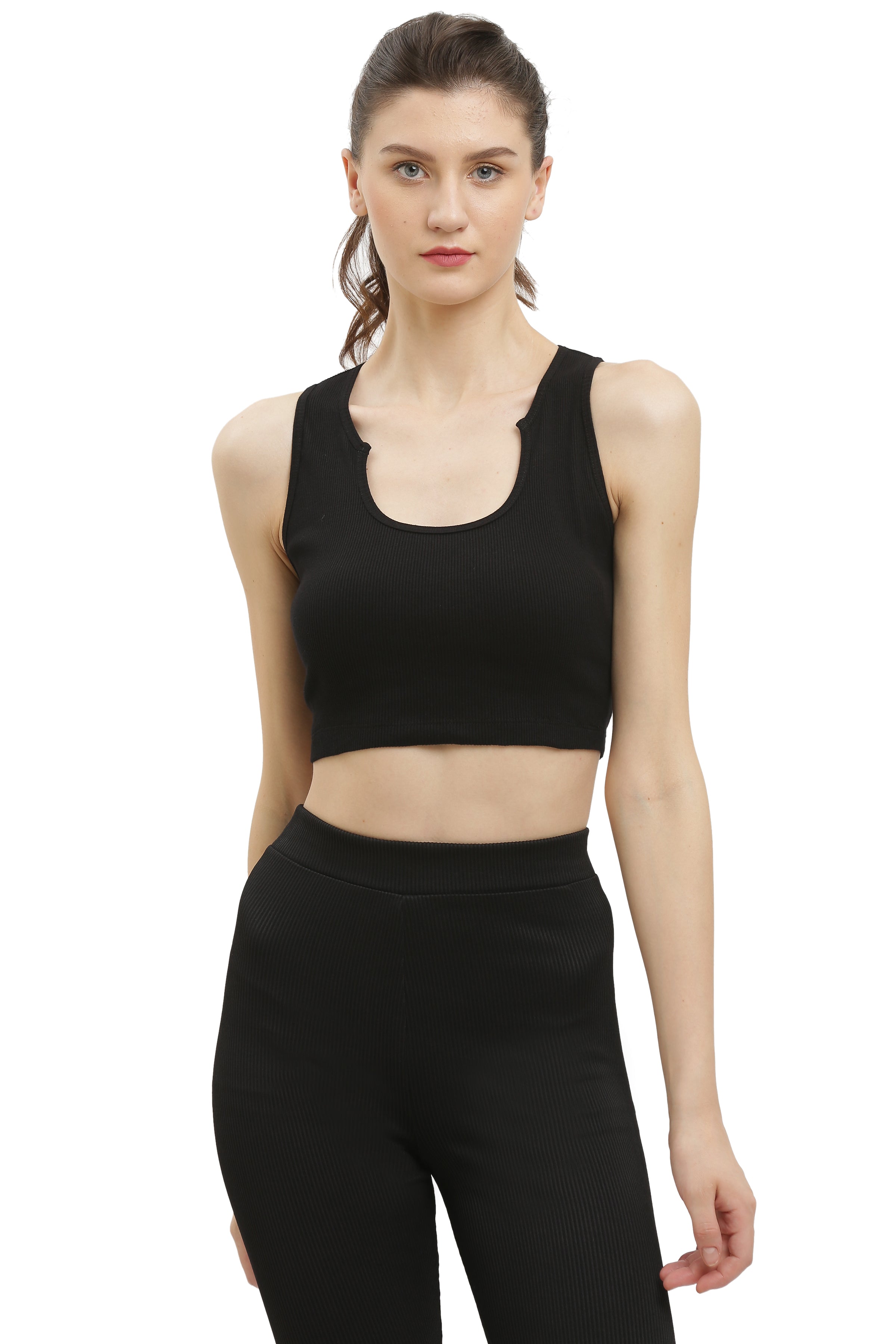A woman wearing a black rib sleeveless crop top and black pants.