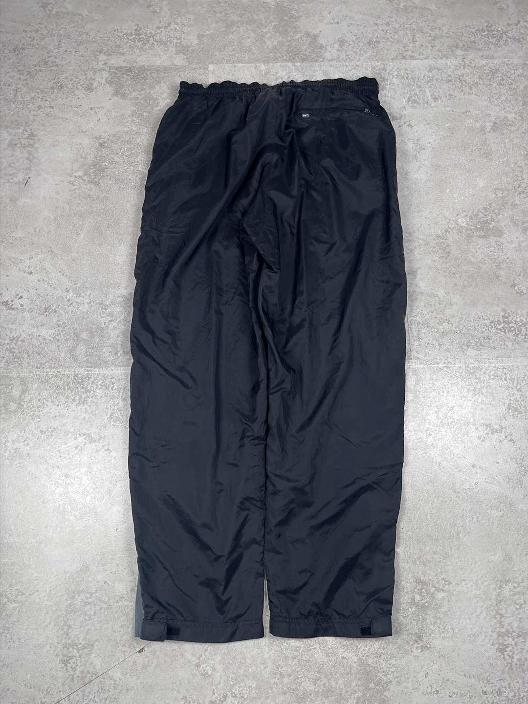 Black pants on a grey concrete floor