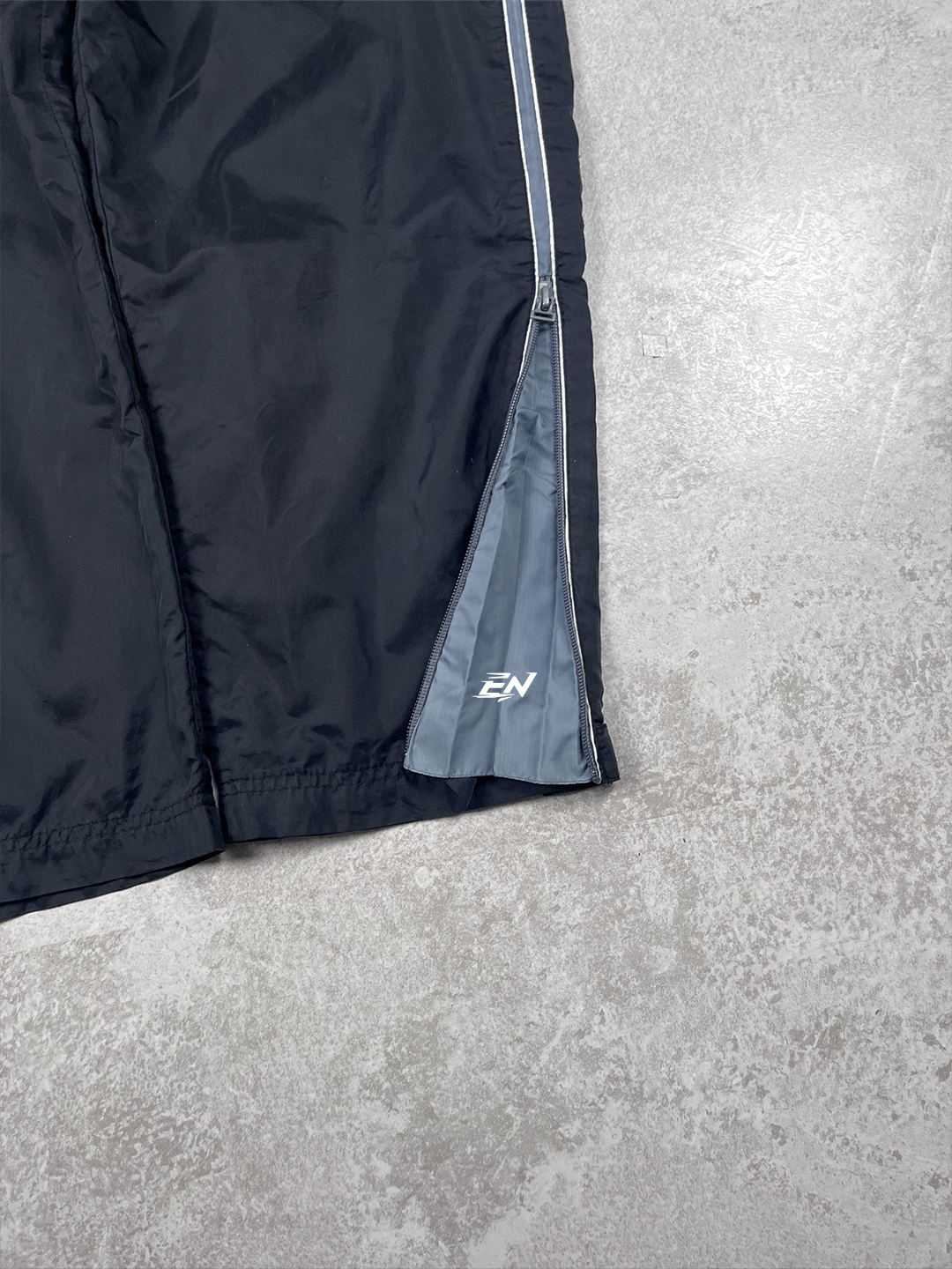 Black jacket with a brand logo on a grey surface