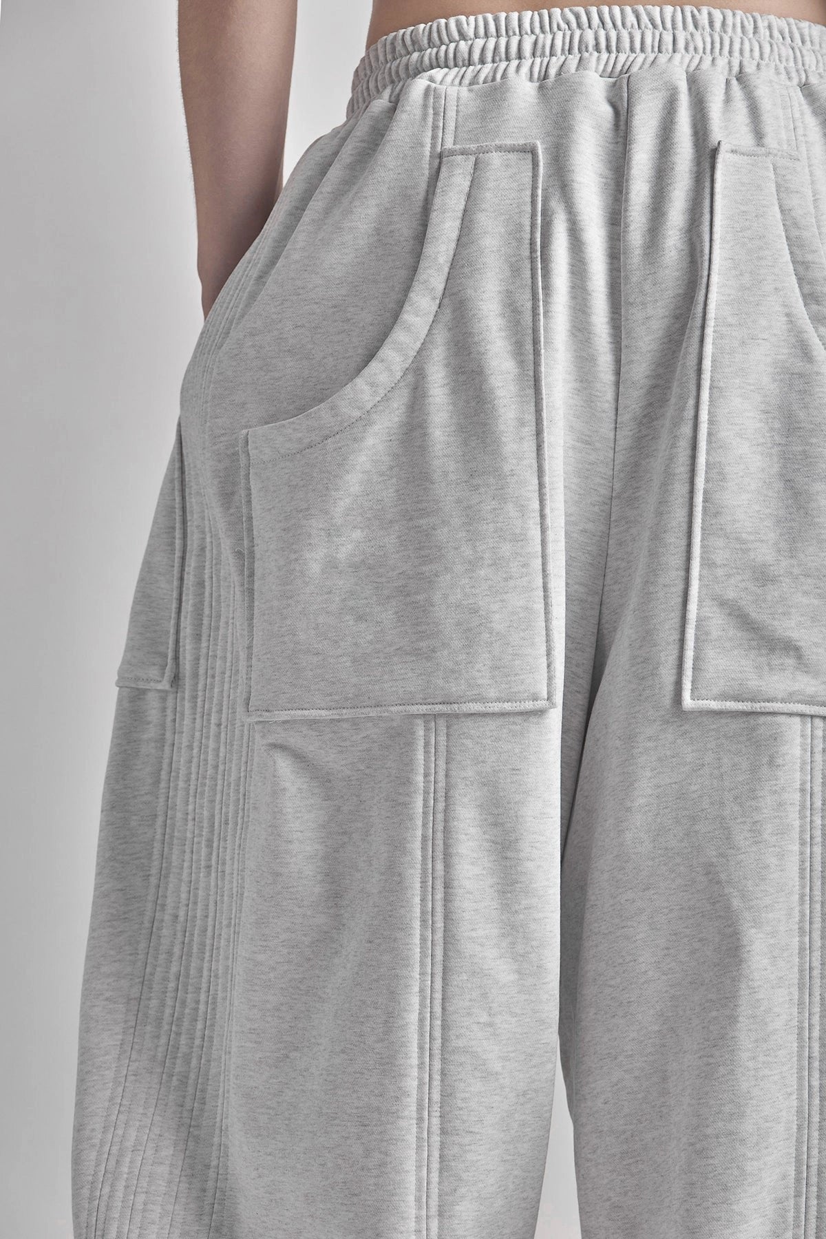 Grey sweatpants with front pocket detail on a plain background