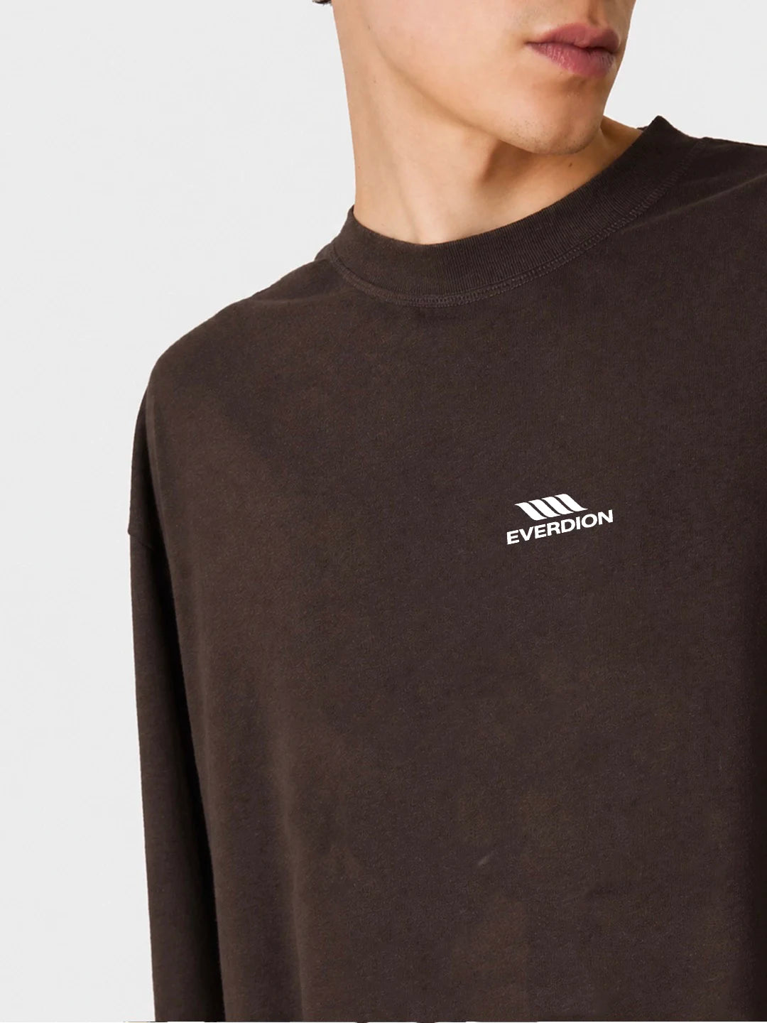 A close-up of a person wearing a dark brown crewneck tshirt with a white Everdion logo on the left chest