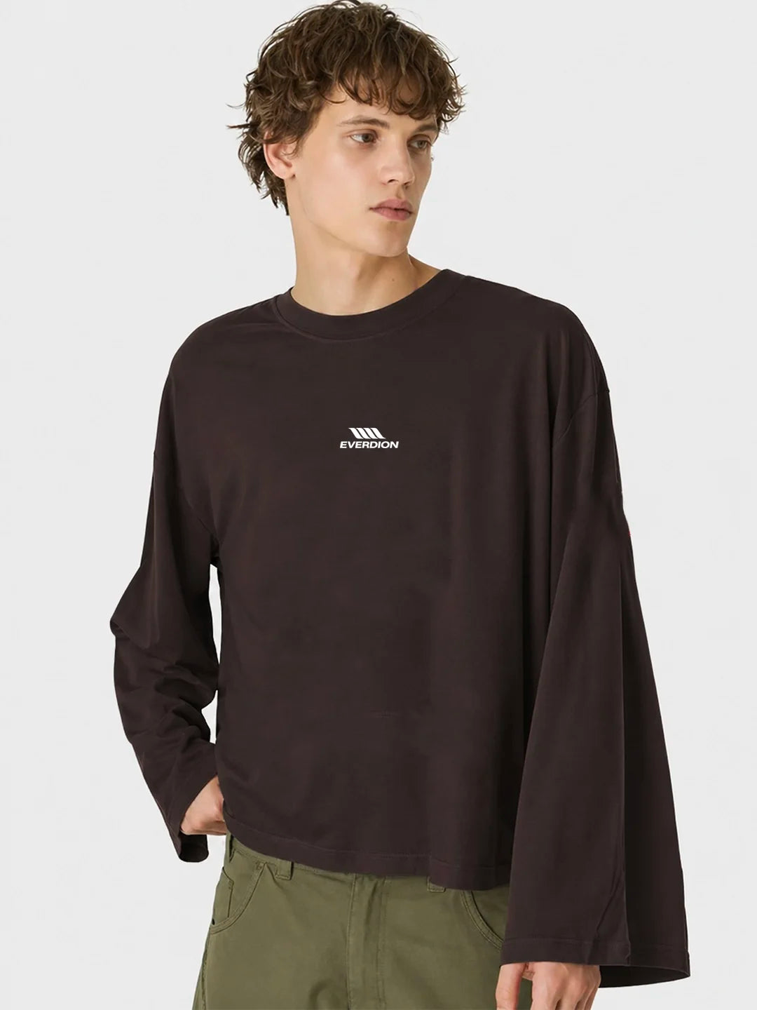 A man wearing a dark brown long-sleeve t-shirt with a small white Everdion logo on the left chest, paired with olive green pants