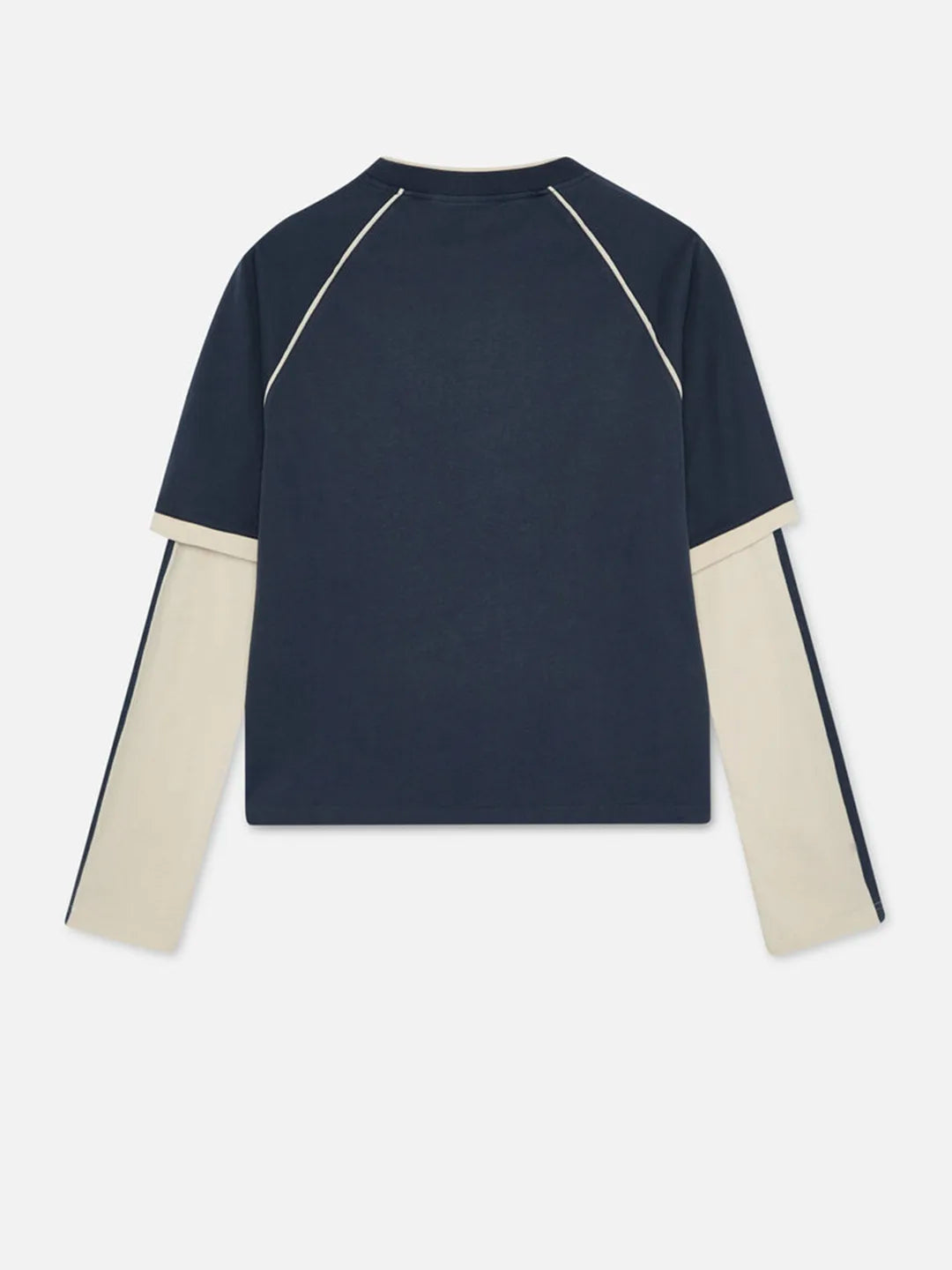 A long-sleeve colorblock top shown from the back, featuring a dark navy blue body with contrasting cream-colored sleeves and thin cream piping details.