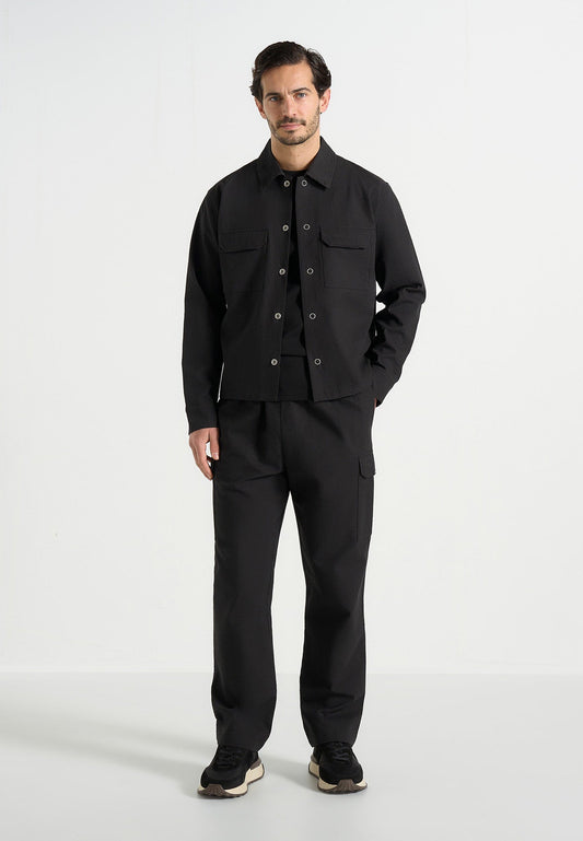 Man wearing a black jacket and pants on a white background