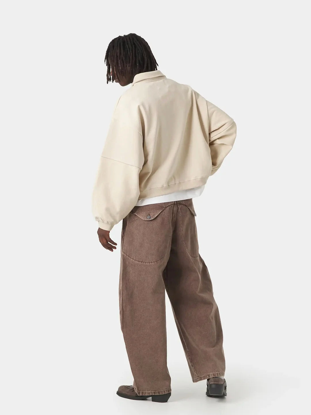 A model wearing a beige polo t-shirt, a white t-shirt, and brown wide-leg corduroy pants 