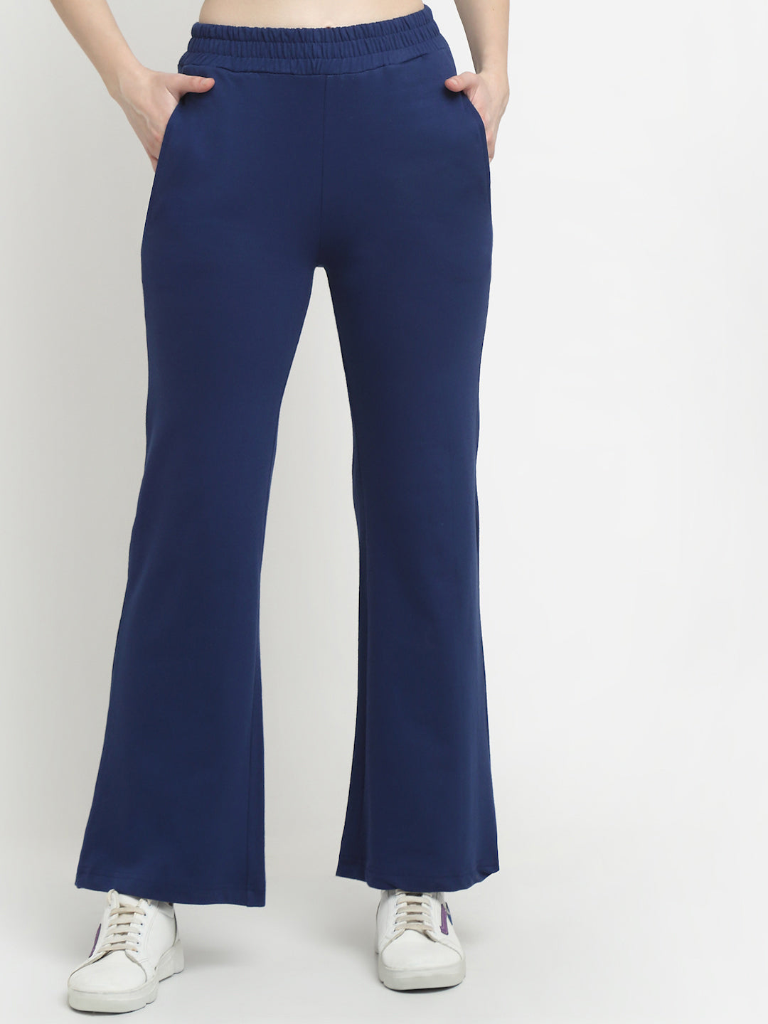 A model wearing navy blue flared track pants and white sneakers.