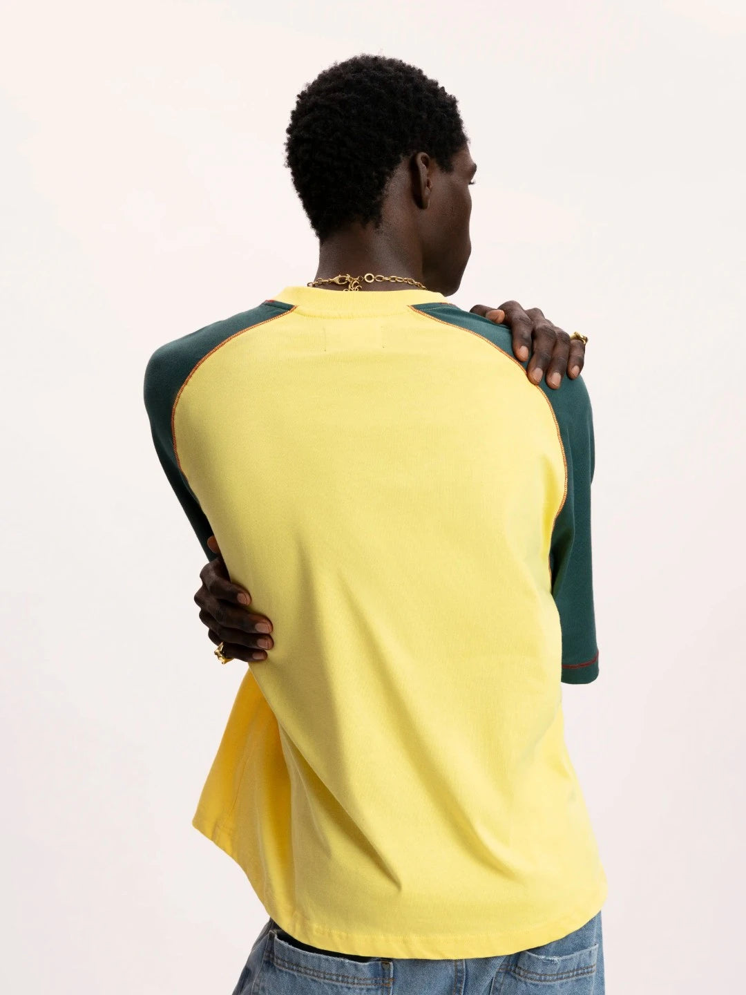 Person wearing a yellow and green baseball-style shirt on a plain background