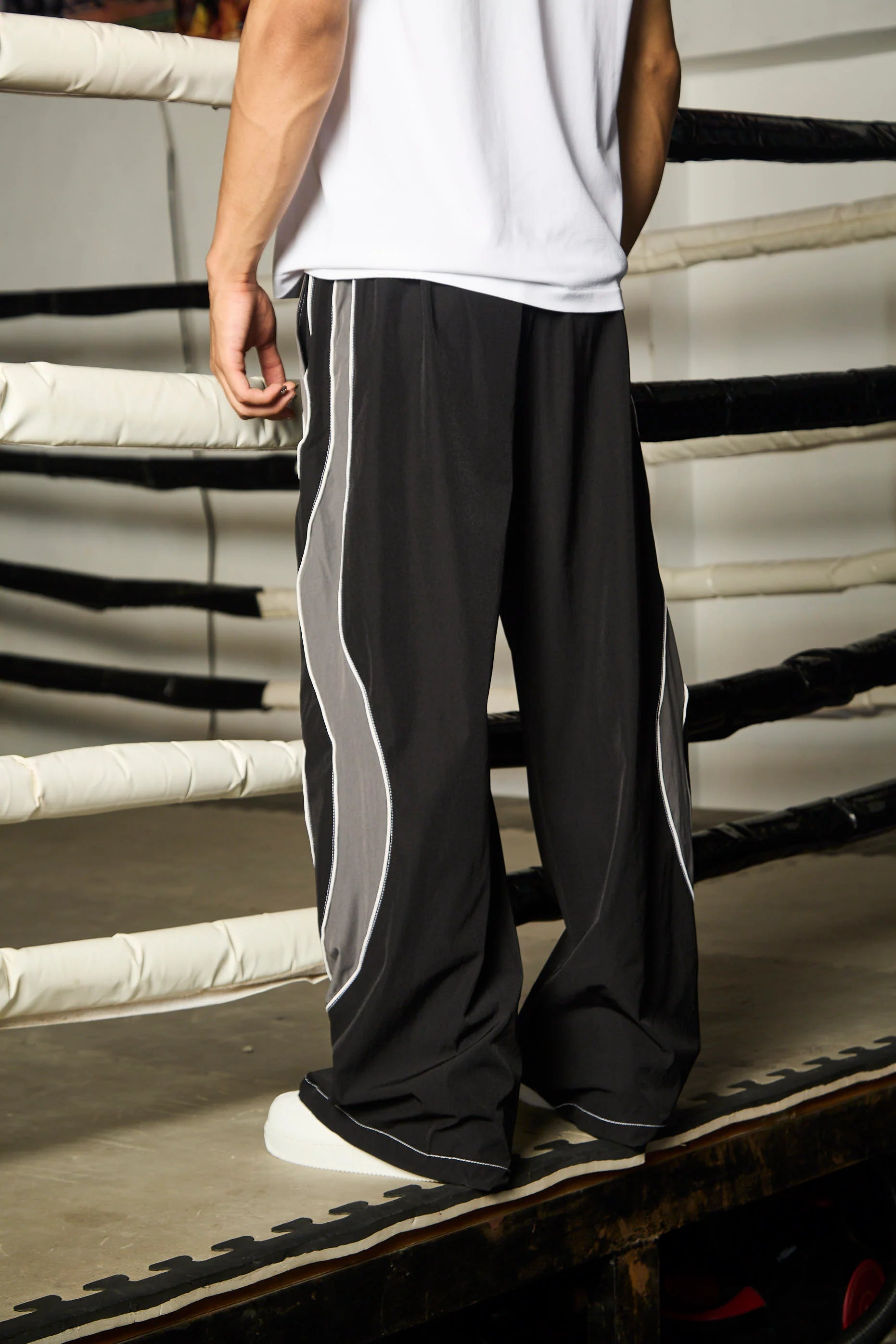 Person wearing black and grey track pants standing in a boxing ring.