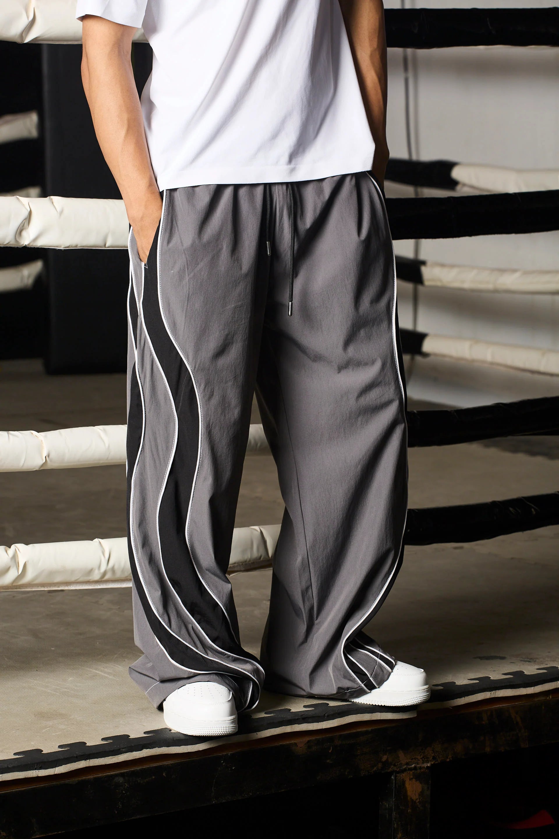 Person wearing grey track pants with black stripes on a staircase.