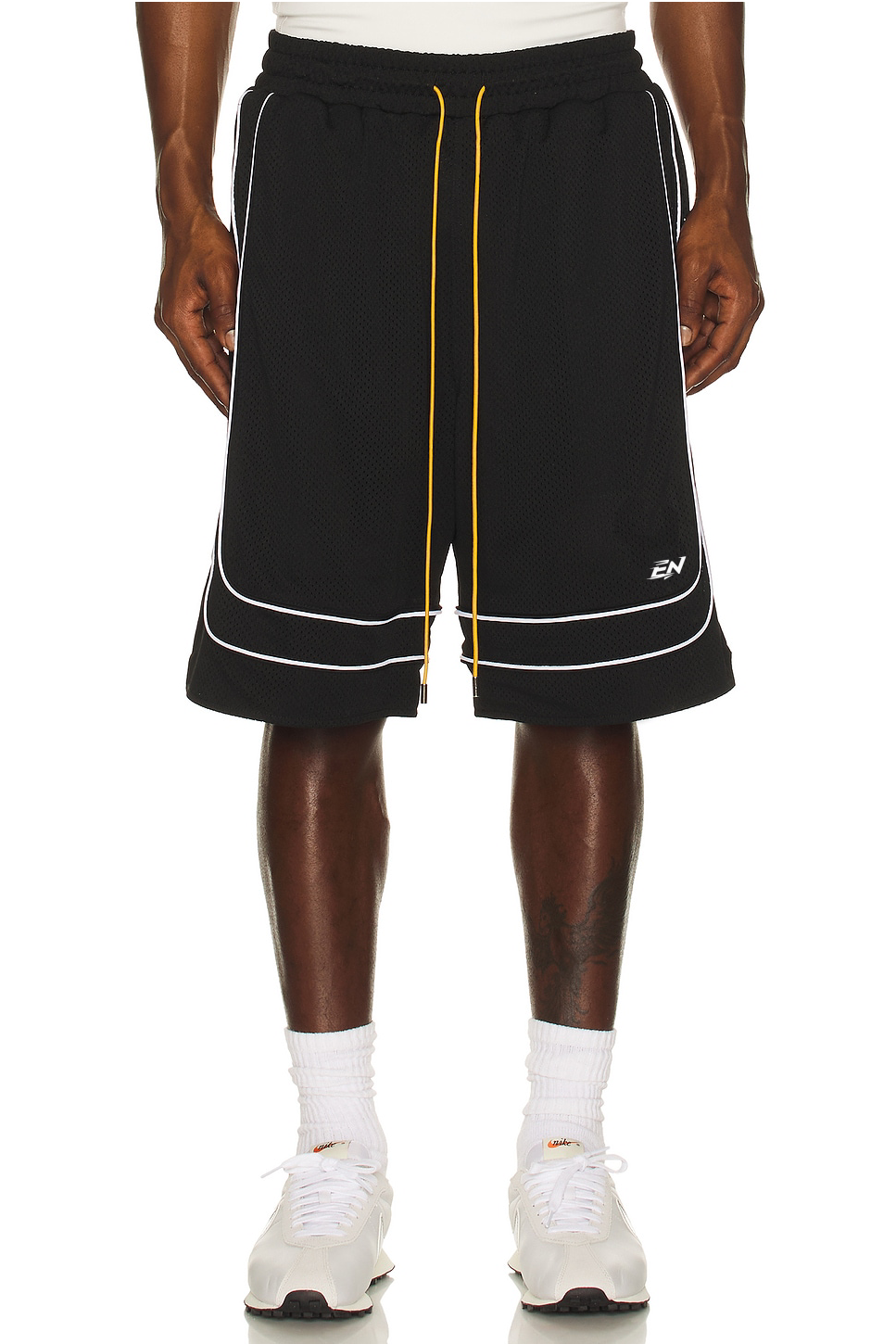 Black shorts with white and yellow accents worn by a person on a white background