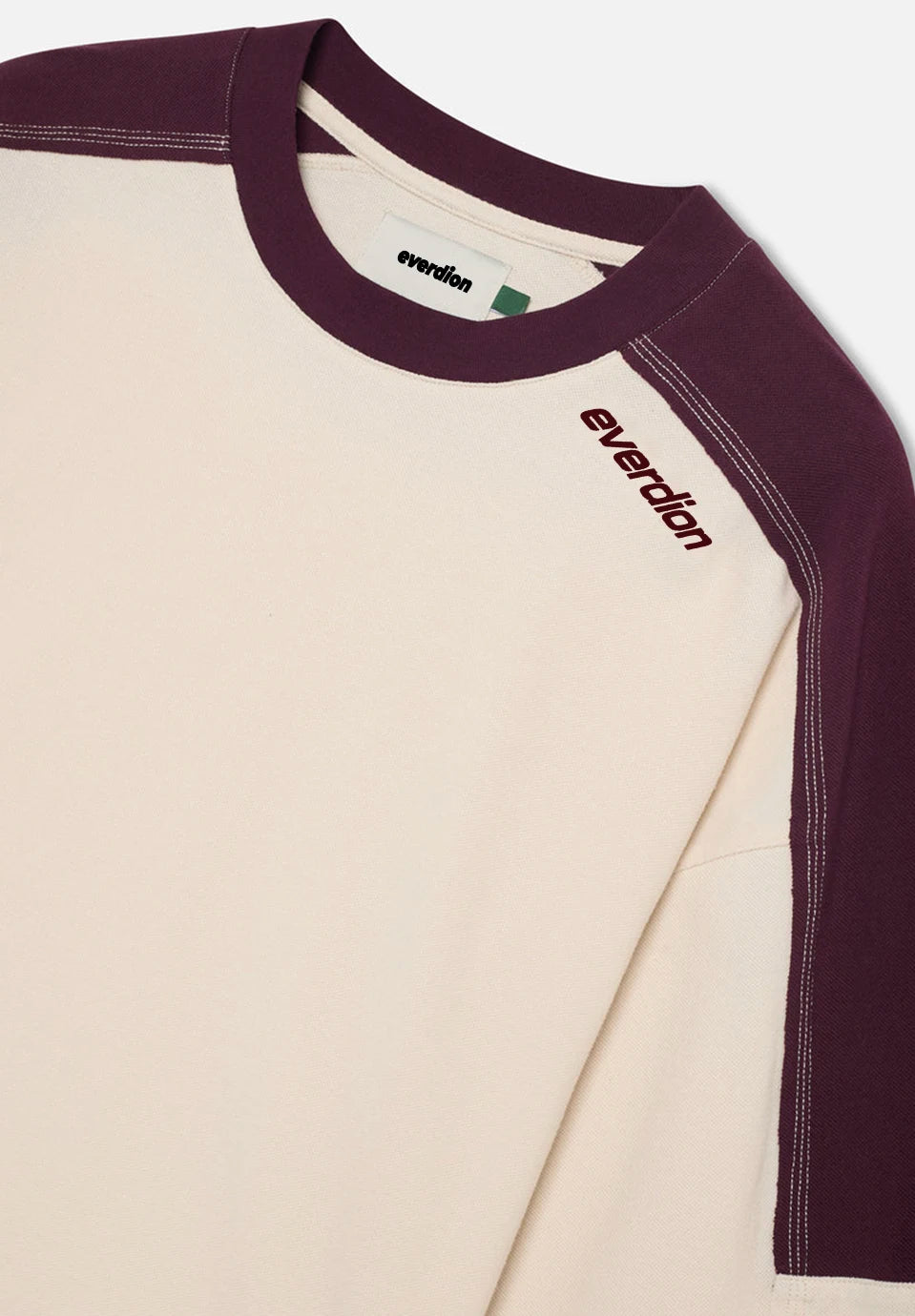 Close-up of a long-sleeve raglan t-shirt by Everdion, featuring an off-white body and deep plum purple sleeves and collar, with the brand name 'everdion' printed on the chest.