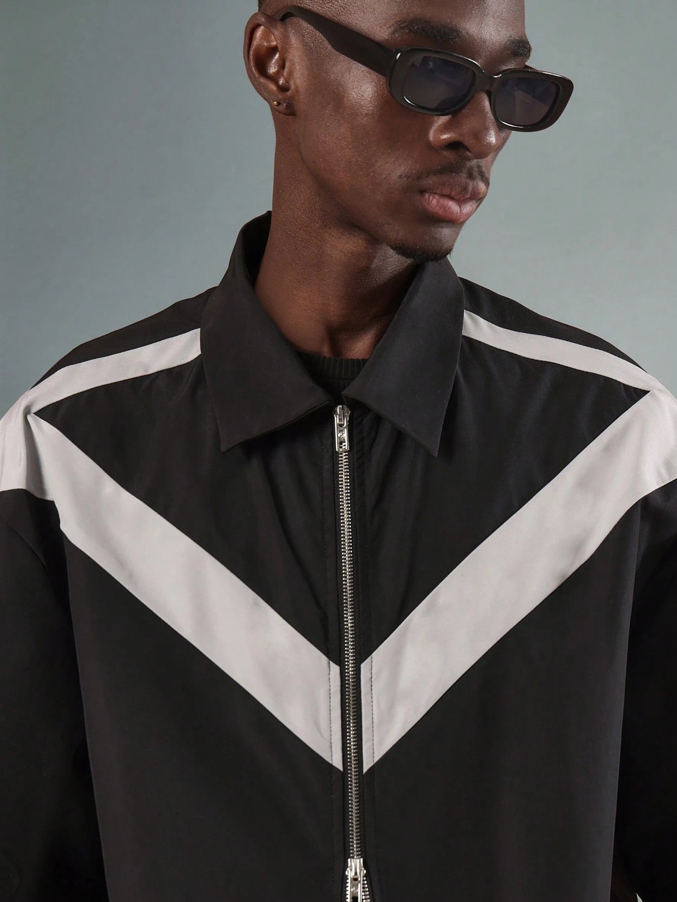Person wearing a black and white jacket with a grey background