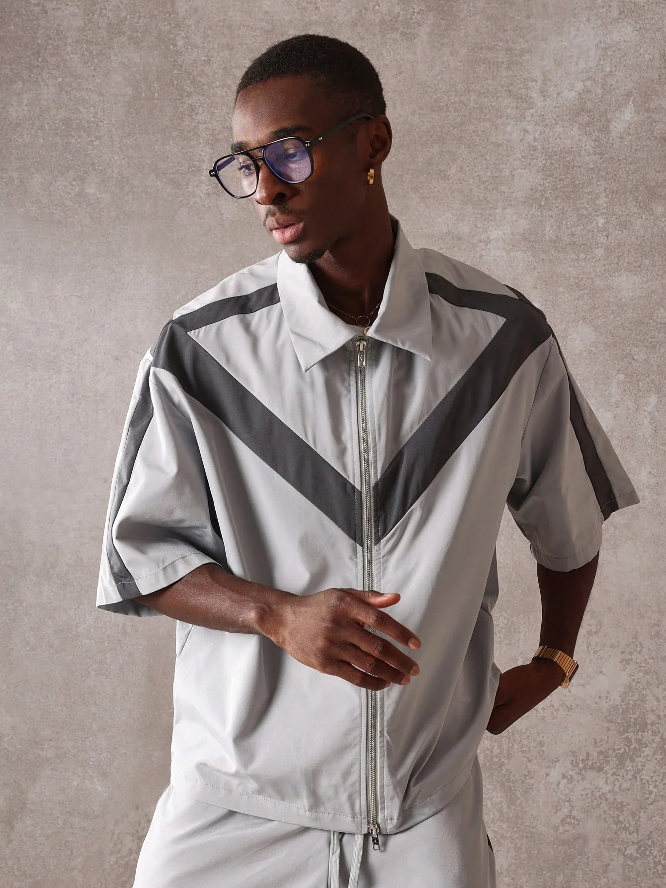 Man wearing a light grey jacket with black chevron patterns against a neutral background